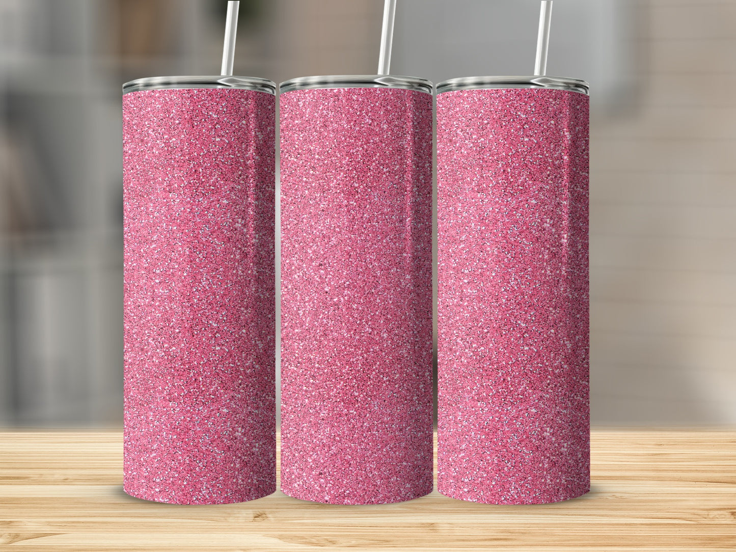 Three pink glitter tumblers with straws stand on a wooden surface.