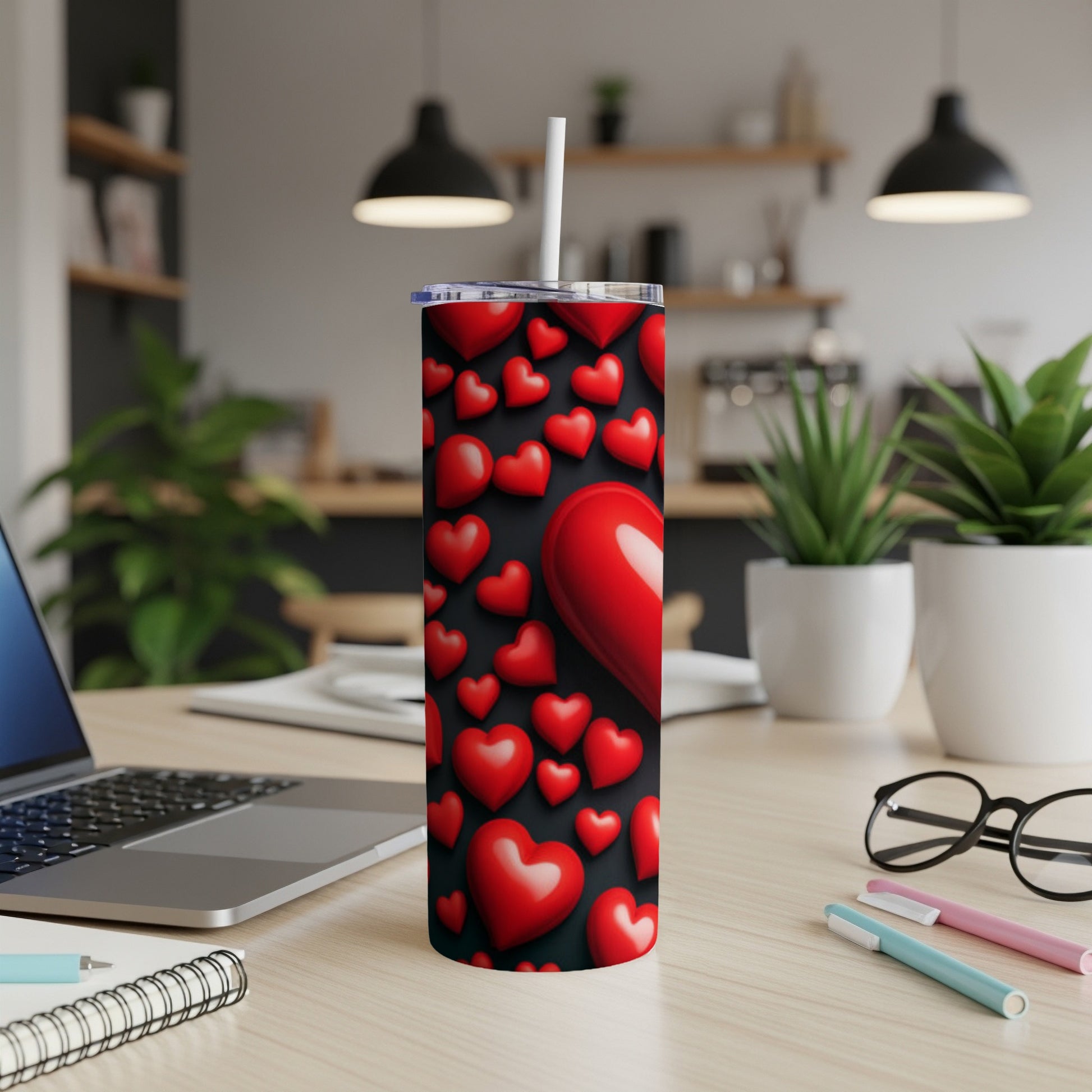 Red hearts pattern on a stainless steel tumbler with straw on a desk.