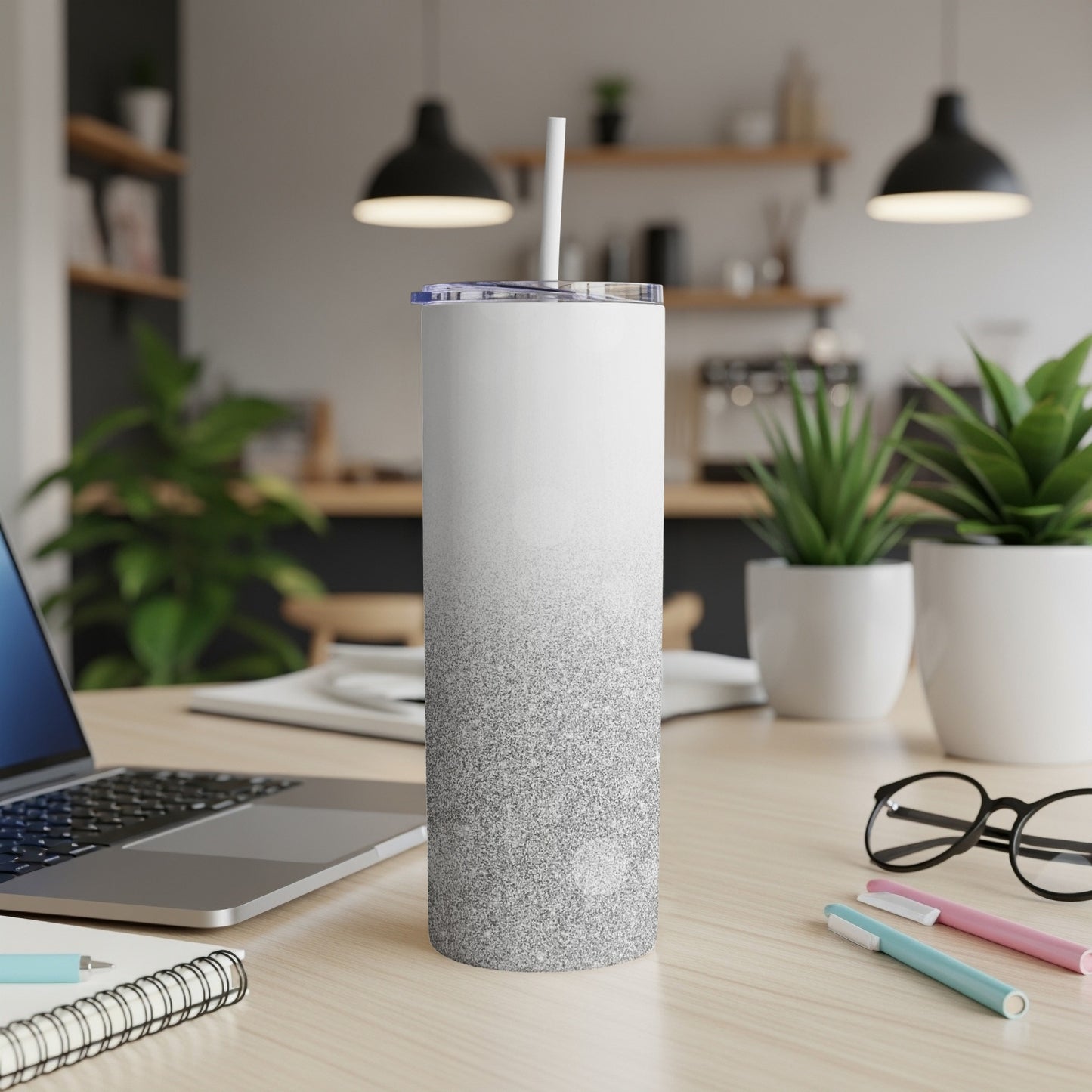 Silver glitter gradient tumbler with white lid and straw on desk.