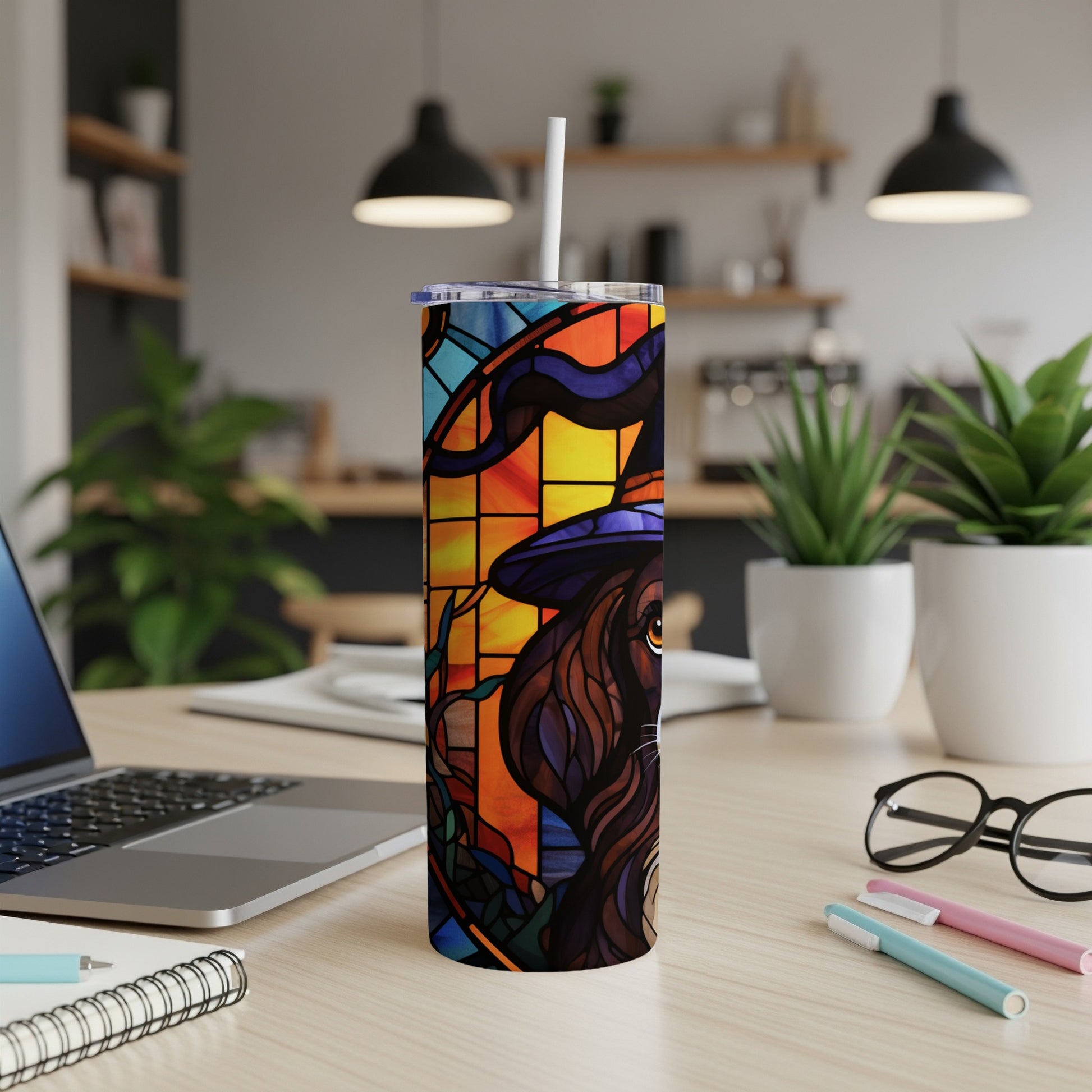 Stained glass tumbler with witch hat and dog, on a desk.