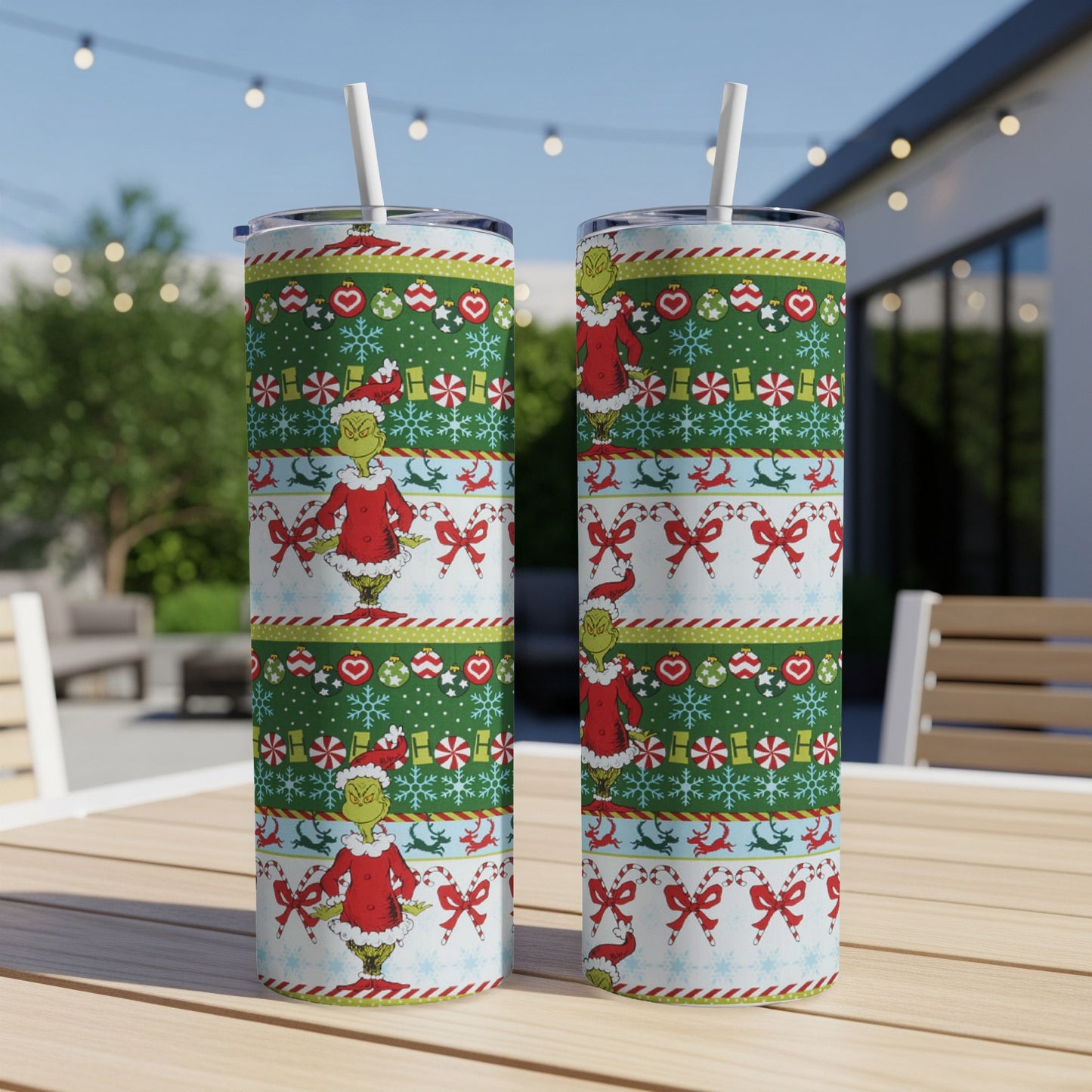 Two Grinch-themed tumblers with a Christmas sweater pattern on a table.
