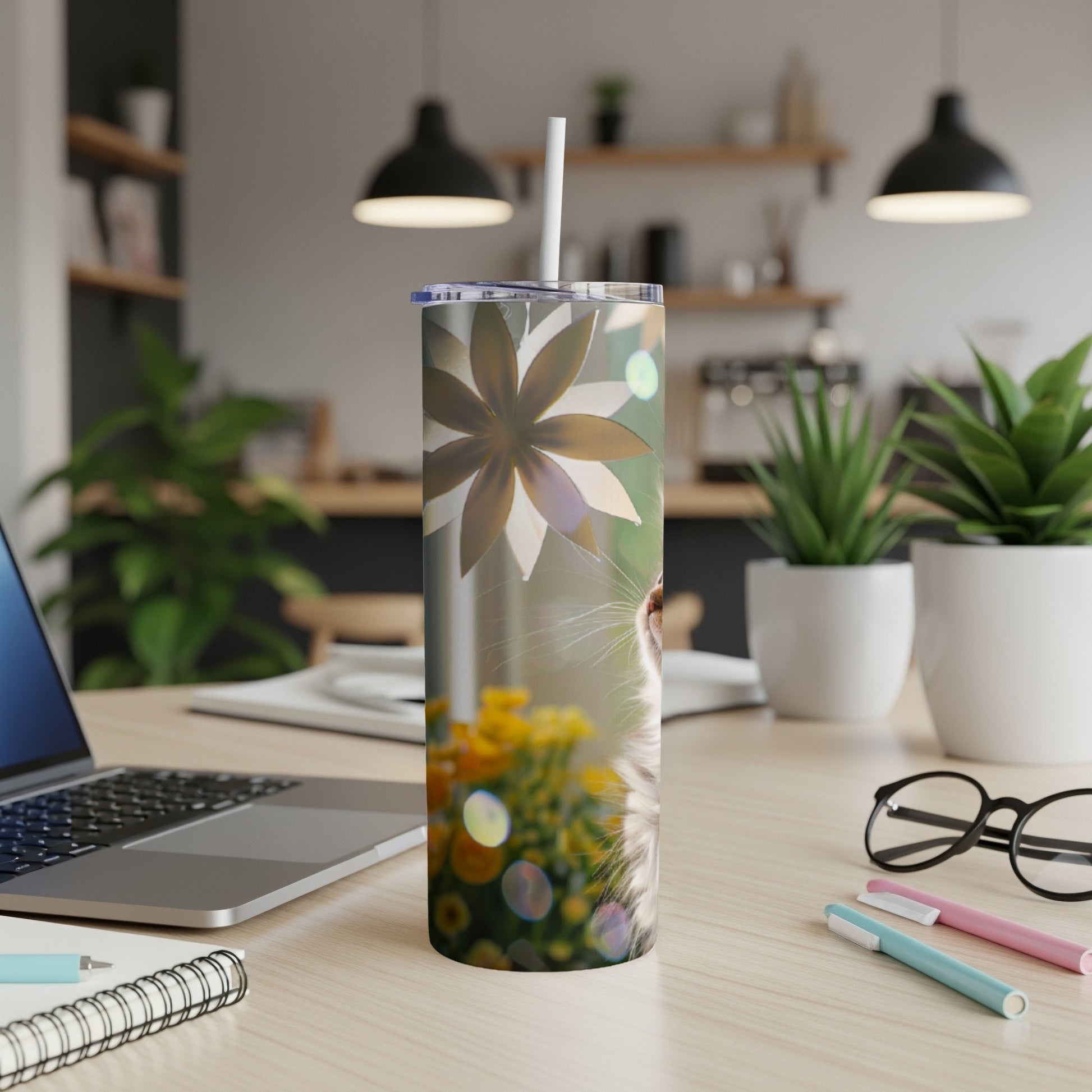 Tumbler with cat's face and floral pattern on desk.