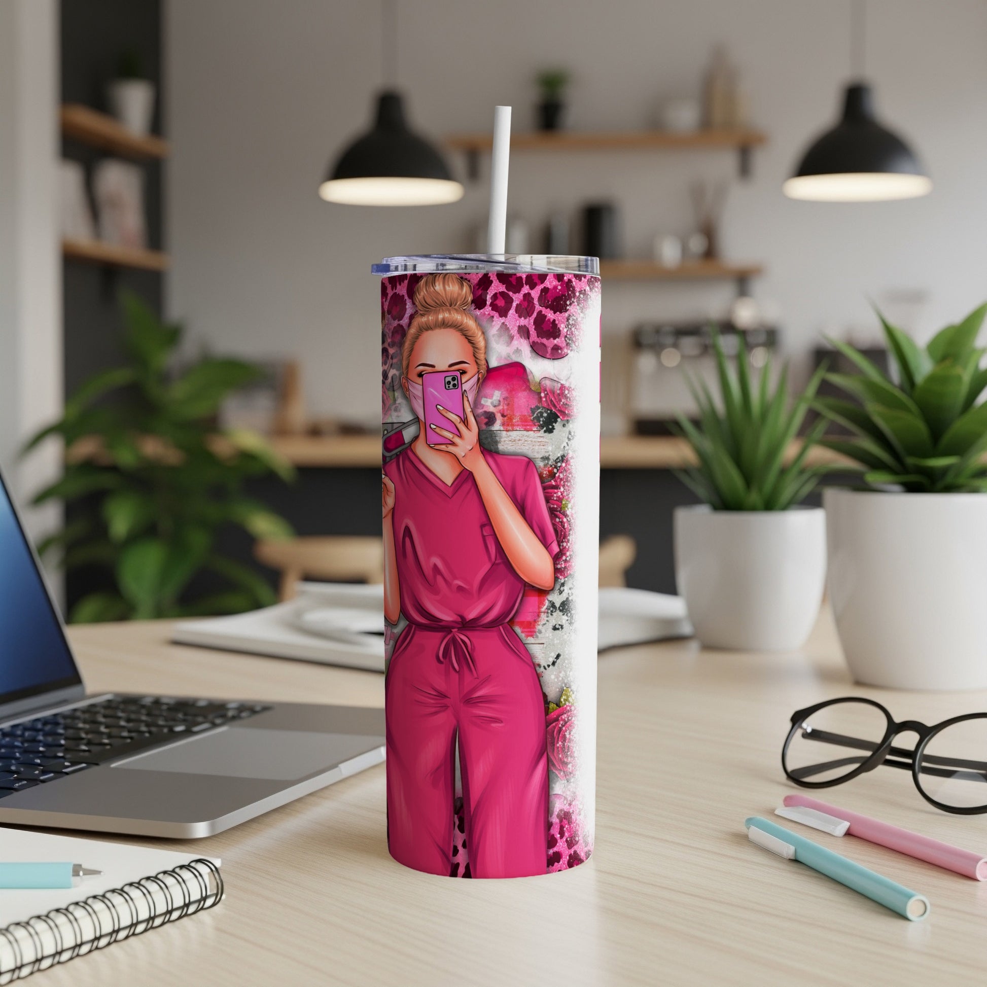 Pink tumbler with nurse design, holding a phone on a desk.