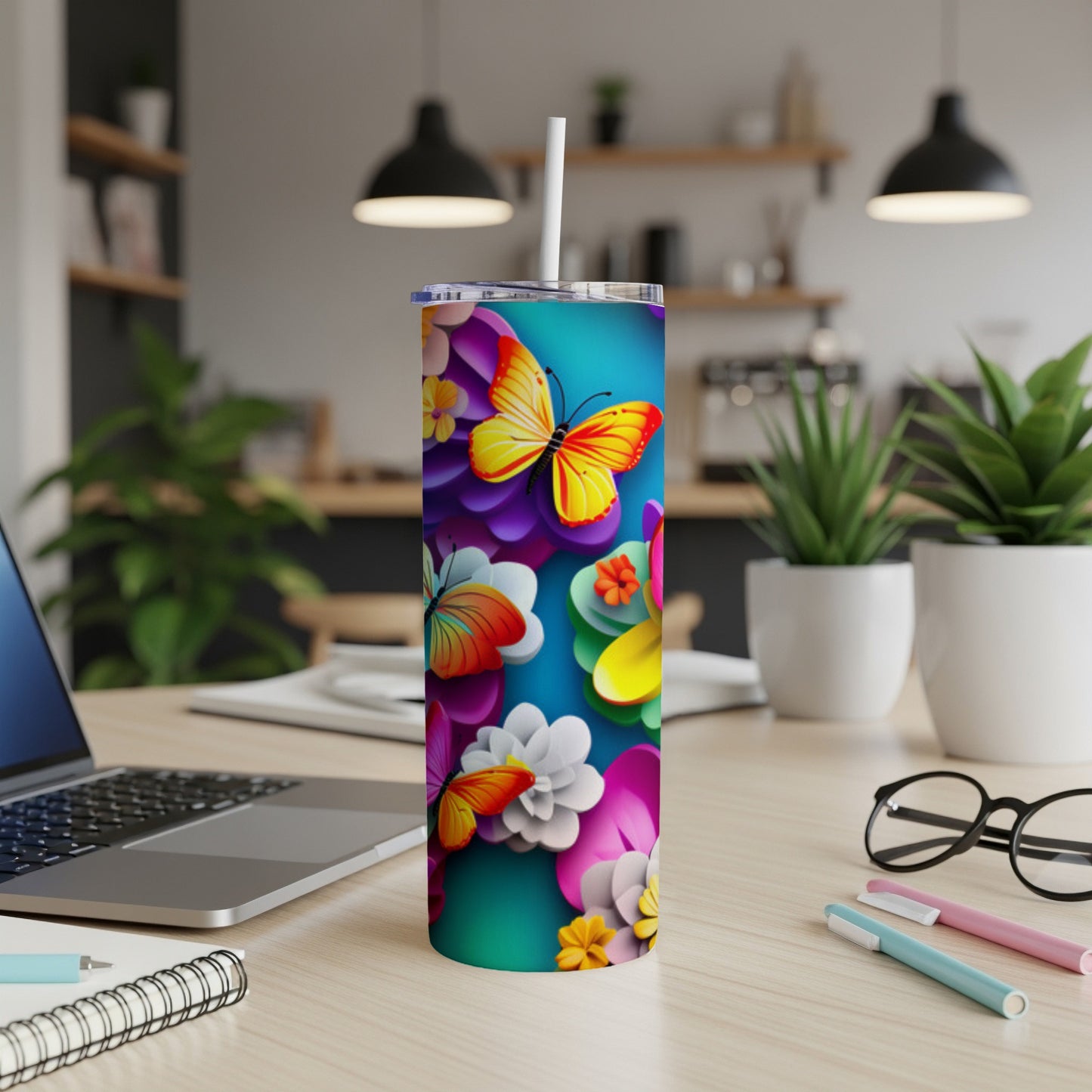 Teal tumbler with colorful butterflies and flowers, straw inserted.