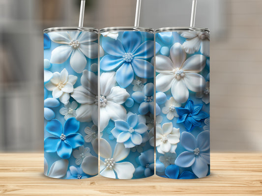 Three blue and white floral tumblers with straws on a wooden surface.