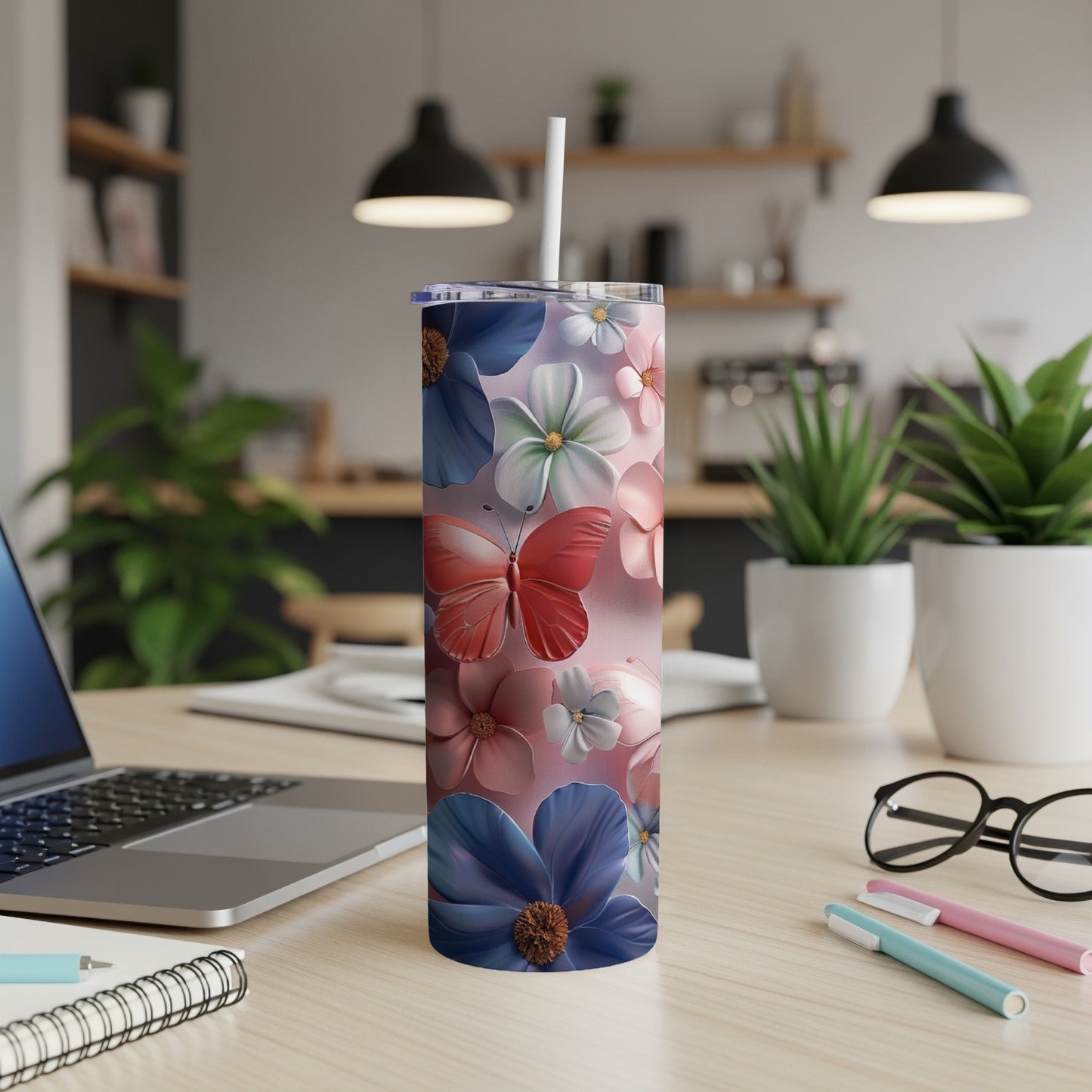 Pink tumbler with colorful floral and butterfly pattern on a desk.