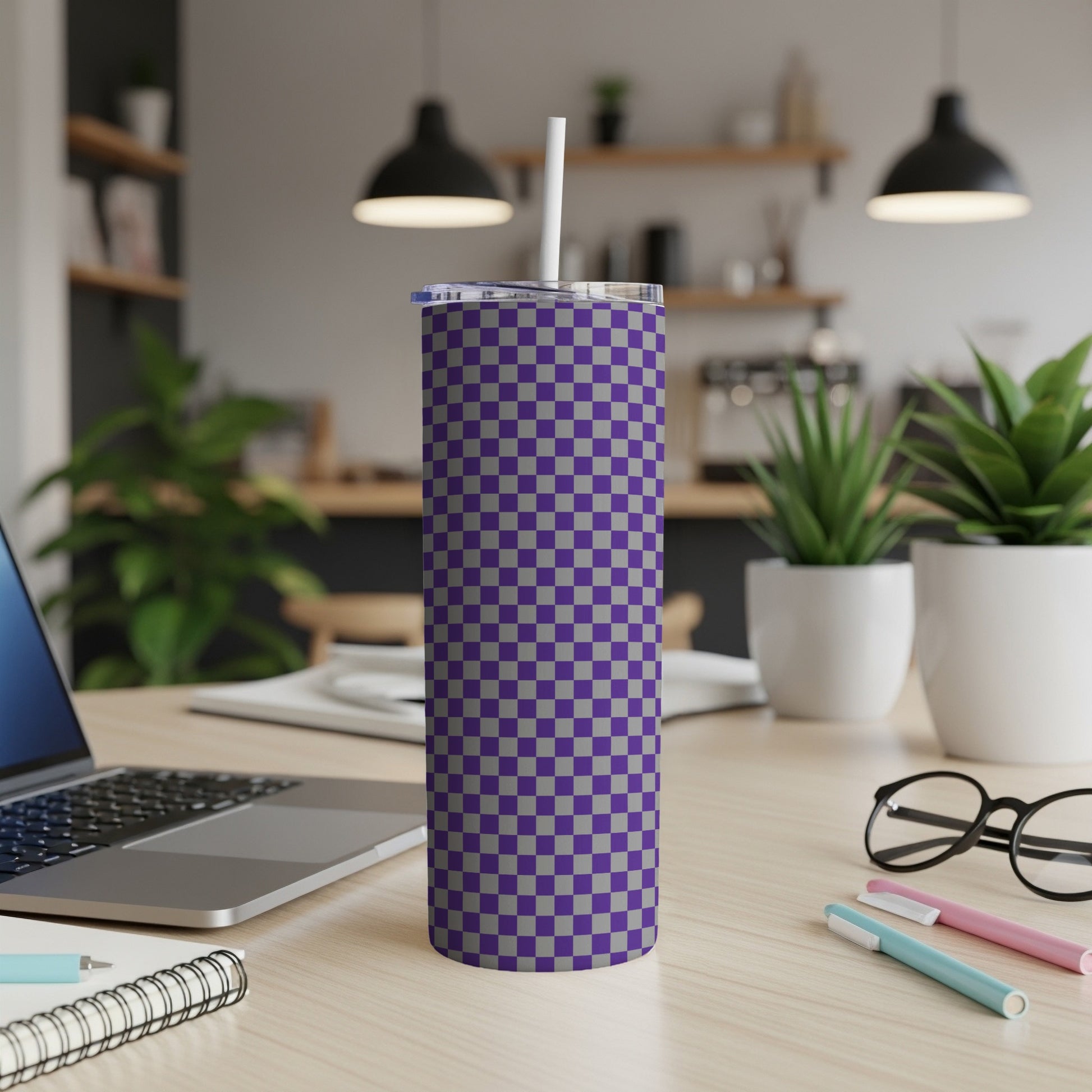 Purple and gray checkered tumbler with a straw on a desk.