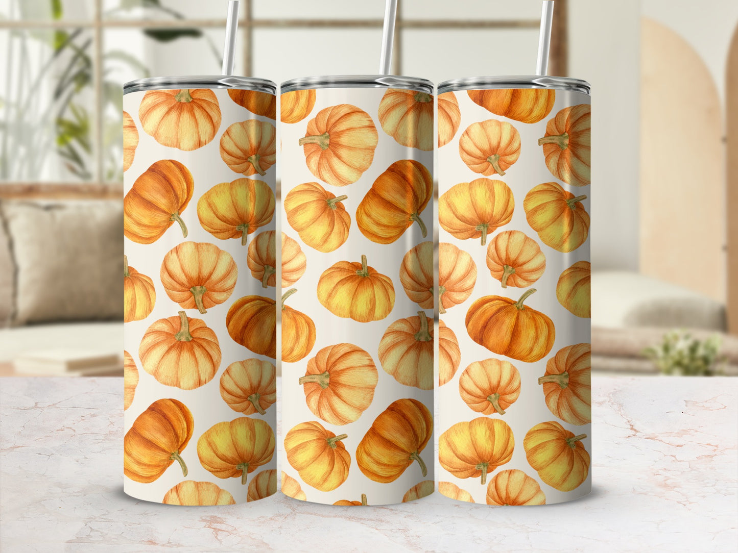 Three tumblers with a watercolor pumpkin pattern on a marble surface.