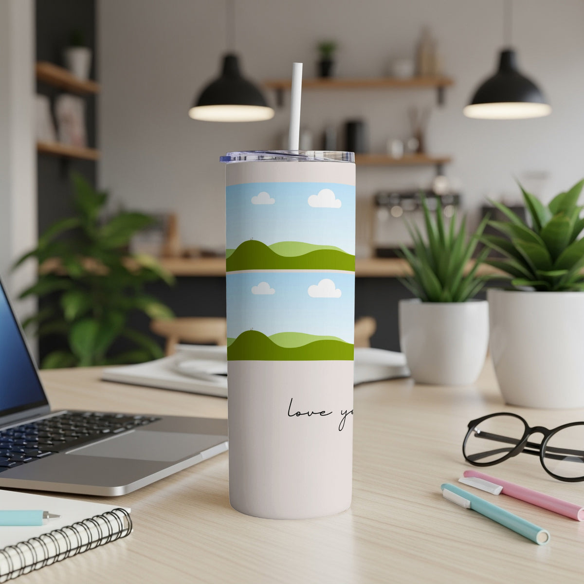 White tumbler with stacked landscape art and "love you" text on a desk.