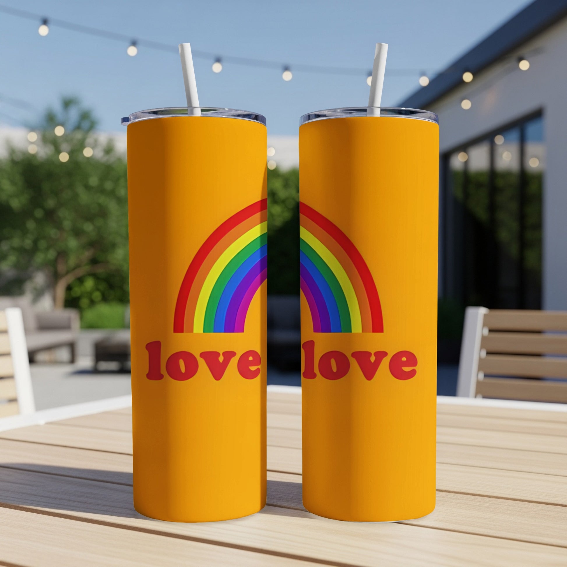 Two orange tumblers with rainbow arches and "love love" text on an outdoor table.