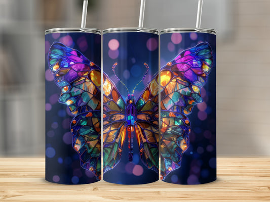 Three colorful stained-glass butterfly tumblers with straws on a wooden surface.