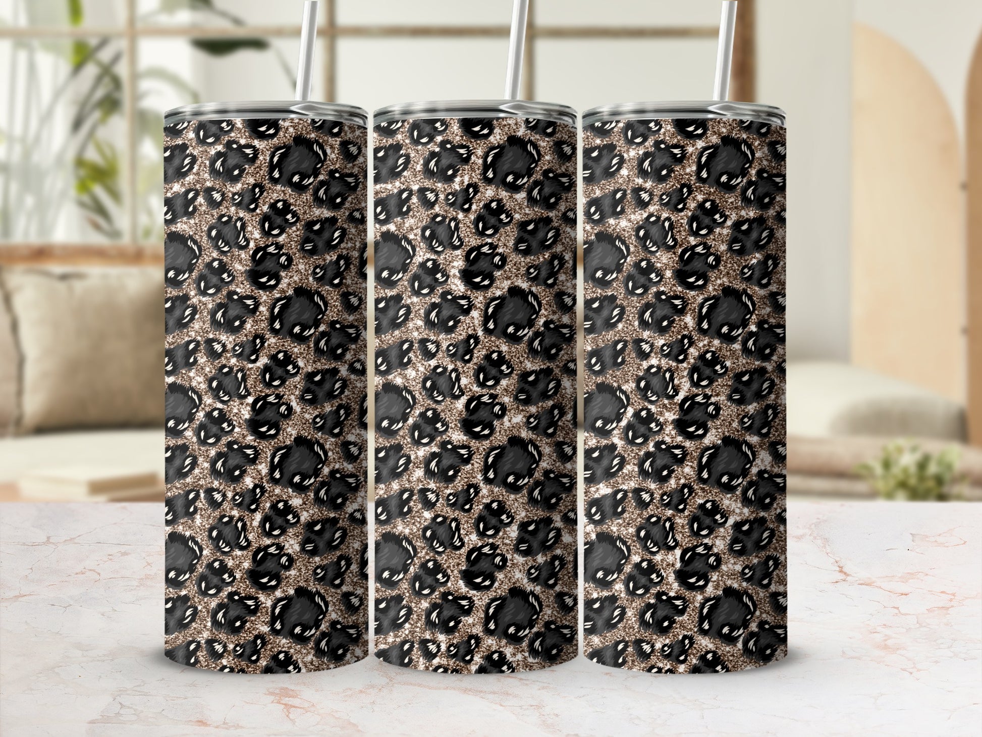 Three tumblers with leopard print and glitter designs, on a marble surface.