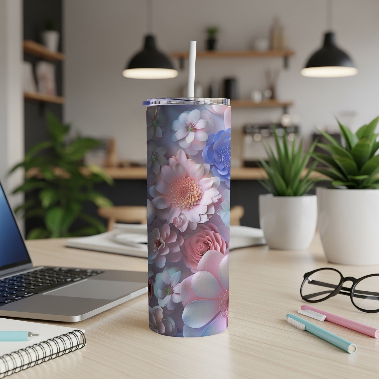 Tall floral tumbler with a straw on a desk with a laptop.