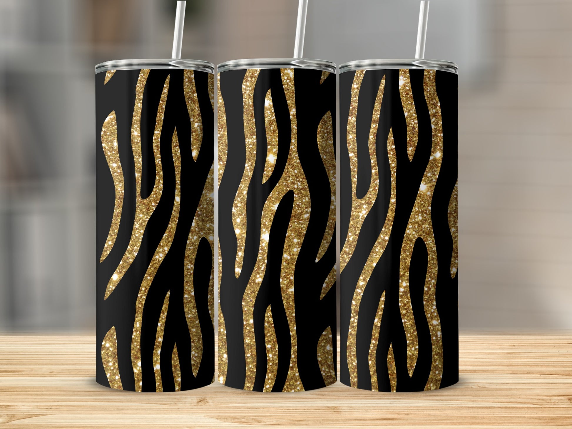 Three tumblers with black and gold glitter zebra print and white straws.