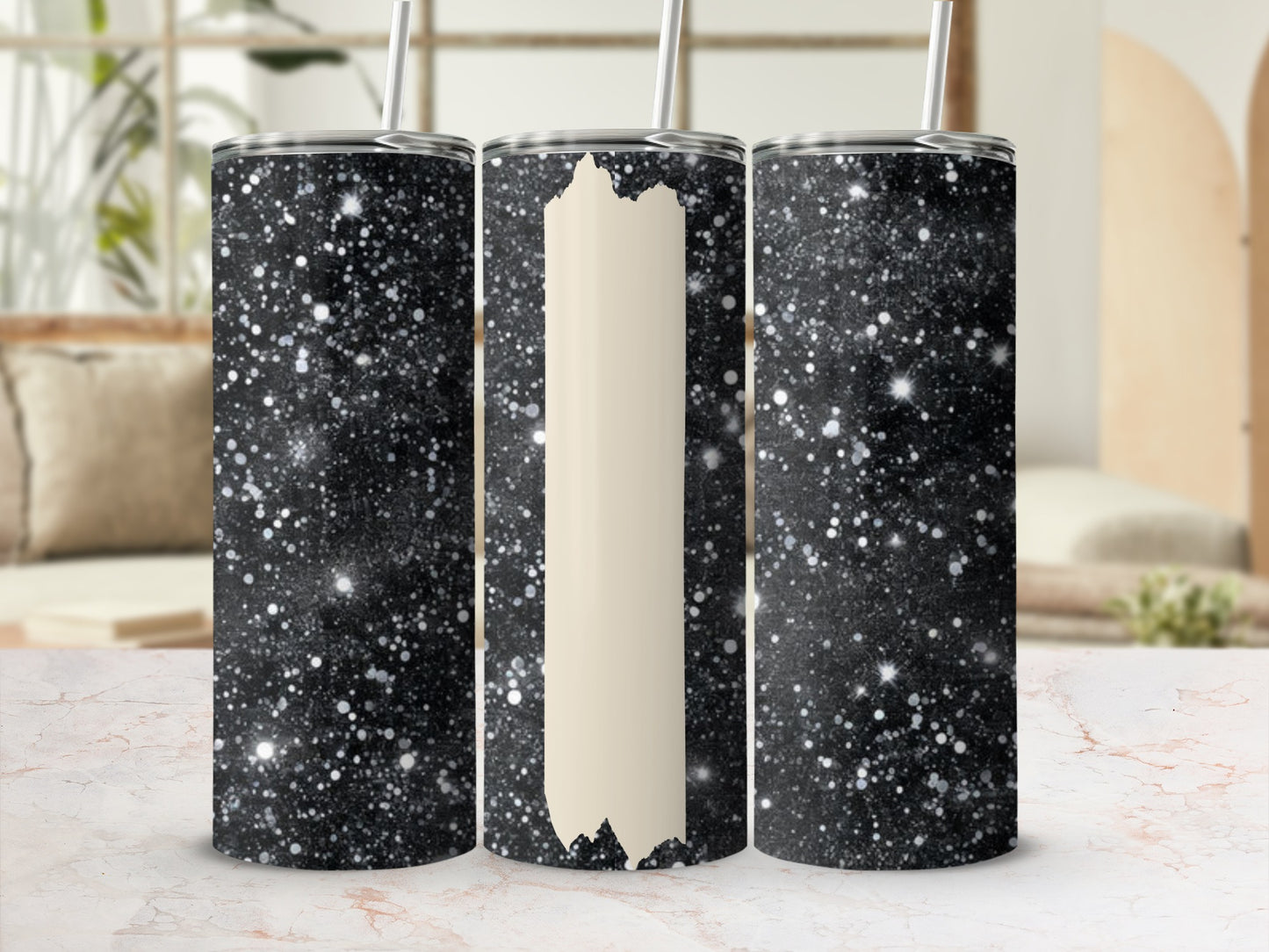 Three glittery black tumblers with straws on a marbled surface.