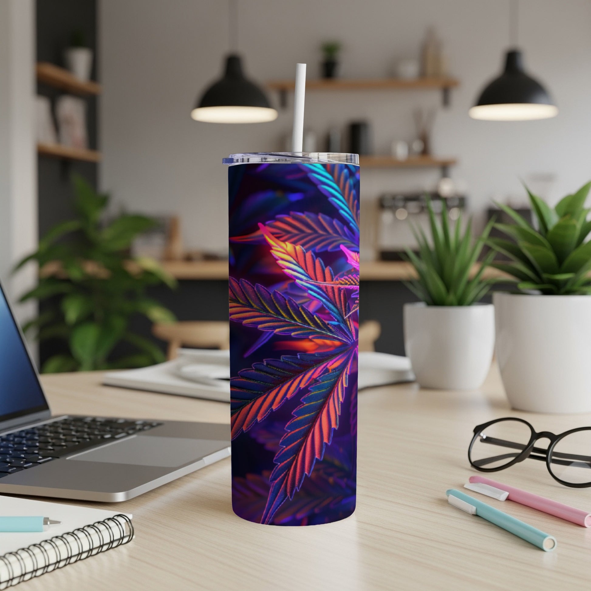 Cannabis leaf design on a skinny tumbler with straw, on a desk.