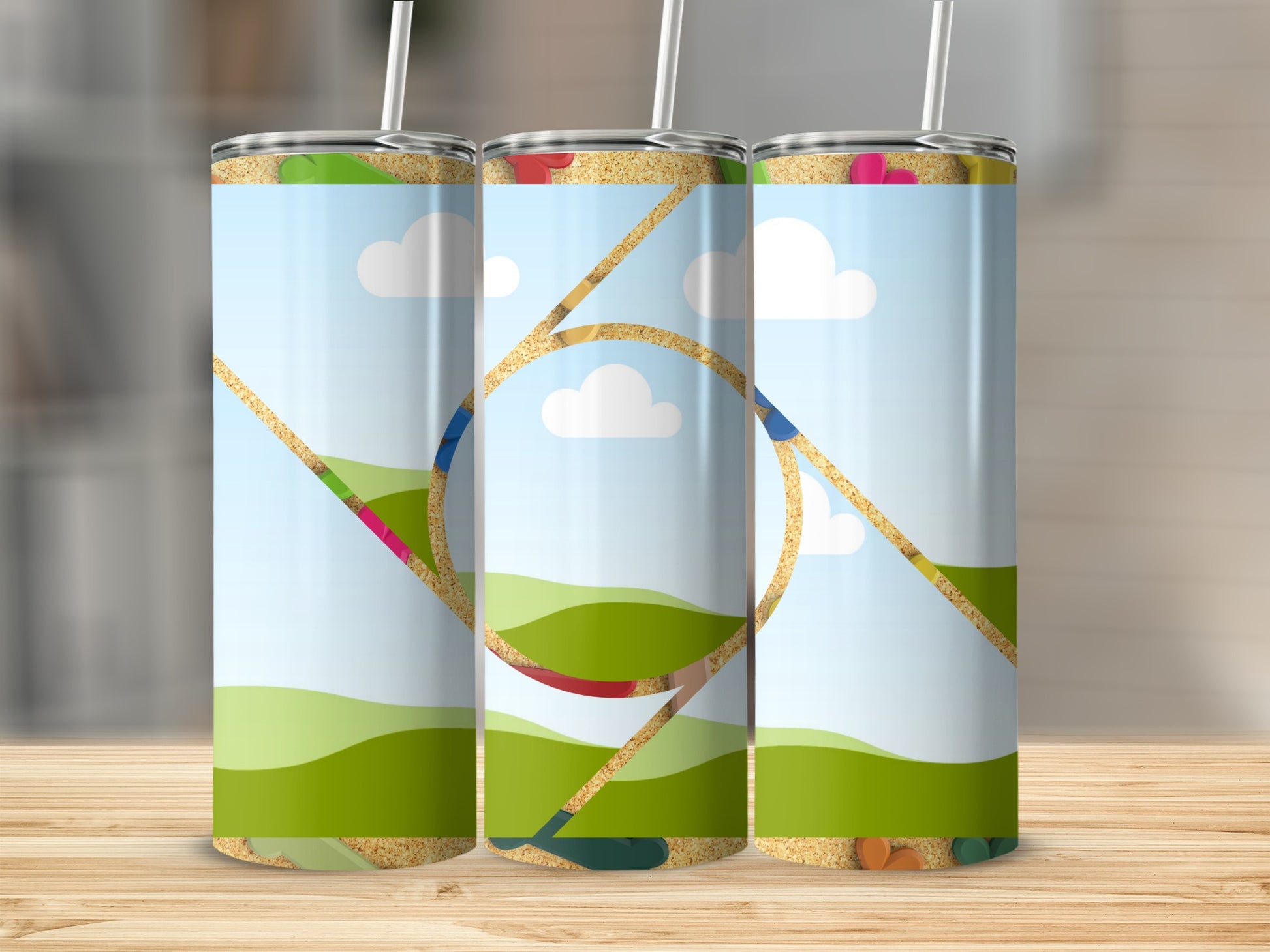 Three tumblers with a colorful outdoor scene, including rolling green hills, sky, clouds, and sand.