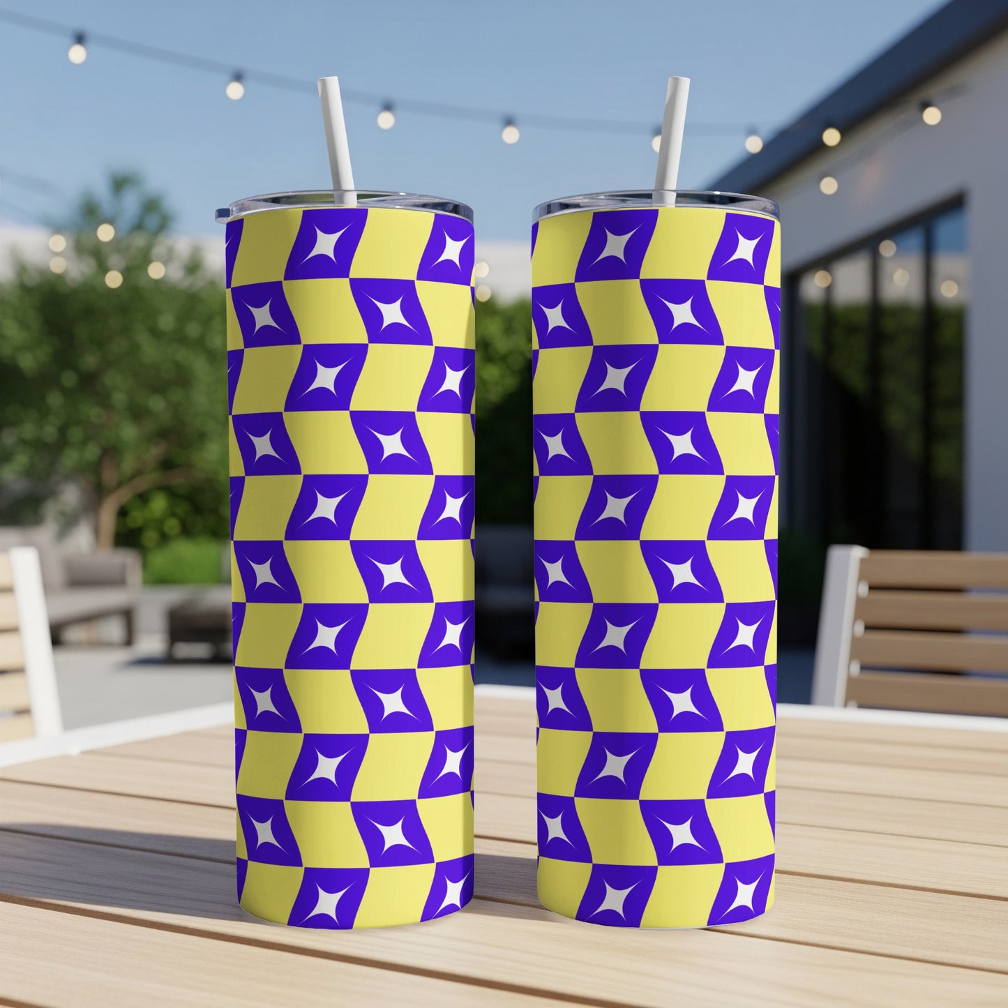 Two purple and yellow geometric patterned tumblers with straws on a wooden table.