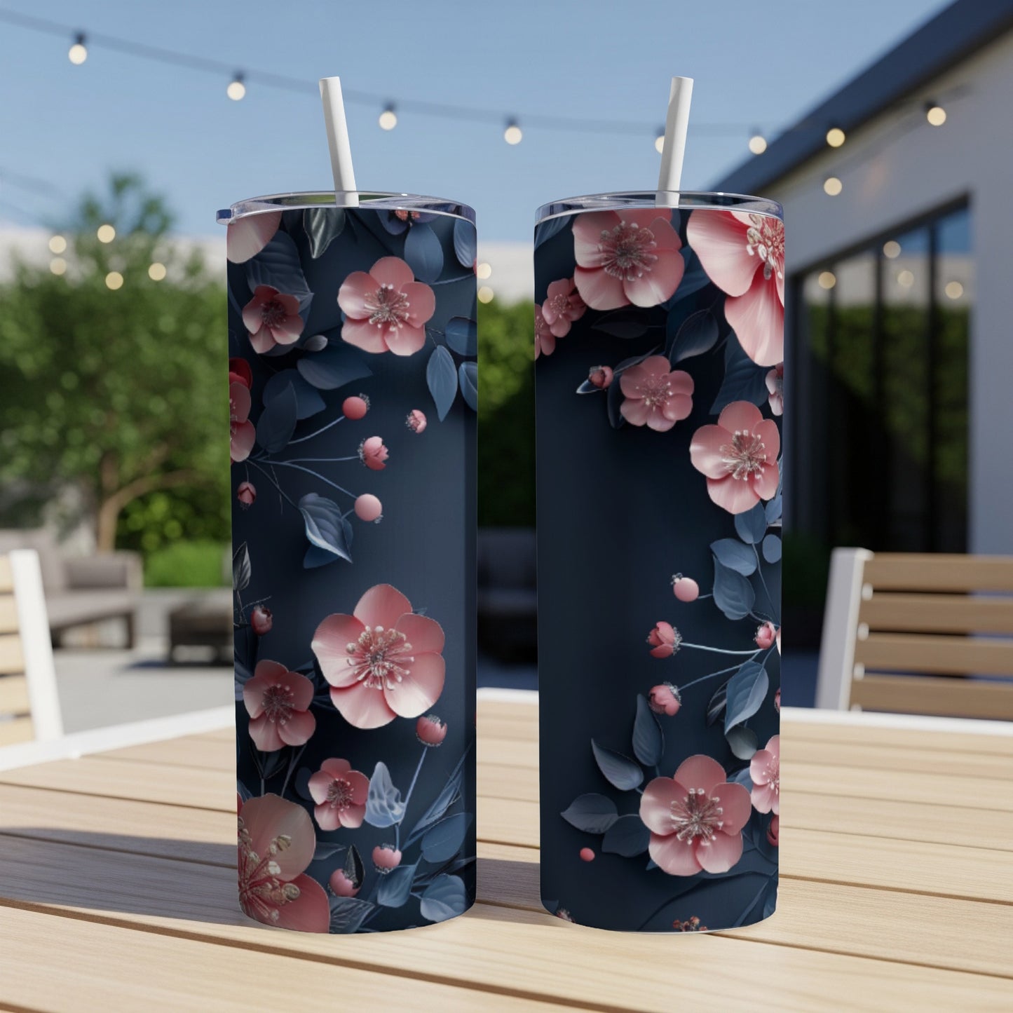 Two navy tumblers with pink floral and berry vine design on a table.