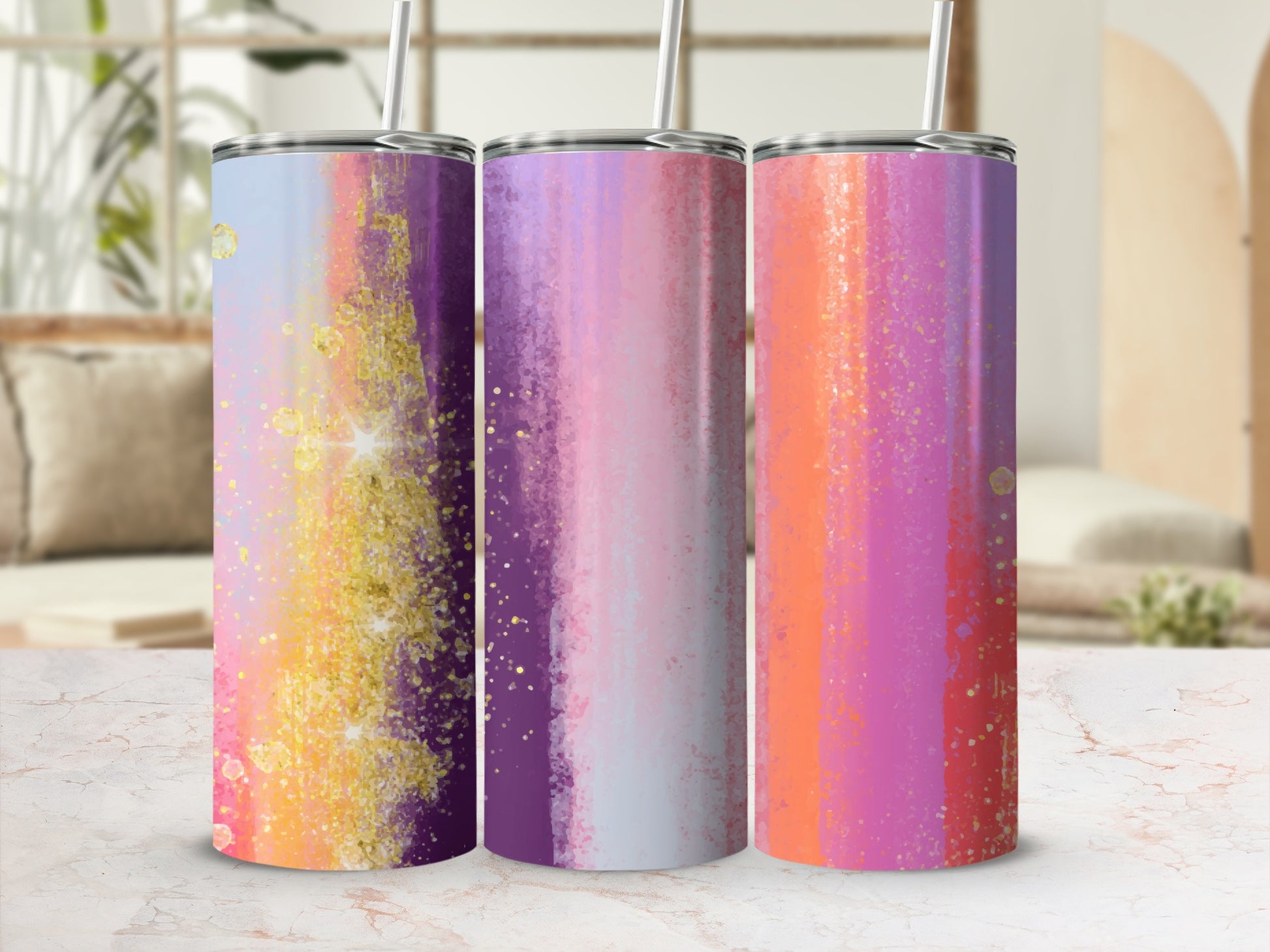 Three tumblers with vibrant abstract watercolor designs and gold glitter accents.