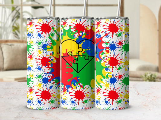 Tumbler with colorful puzzle heart on splatter paint background.
