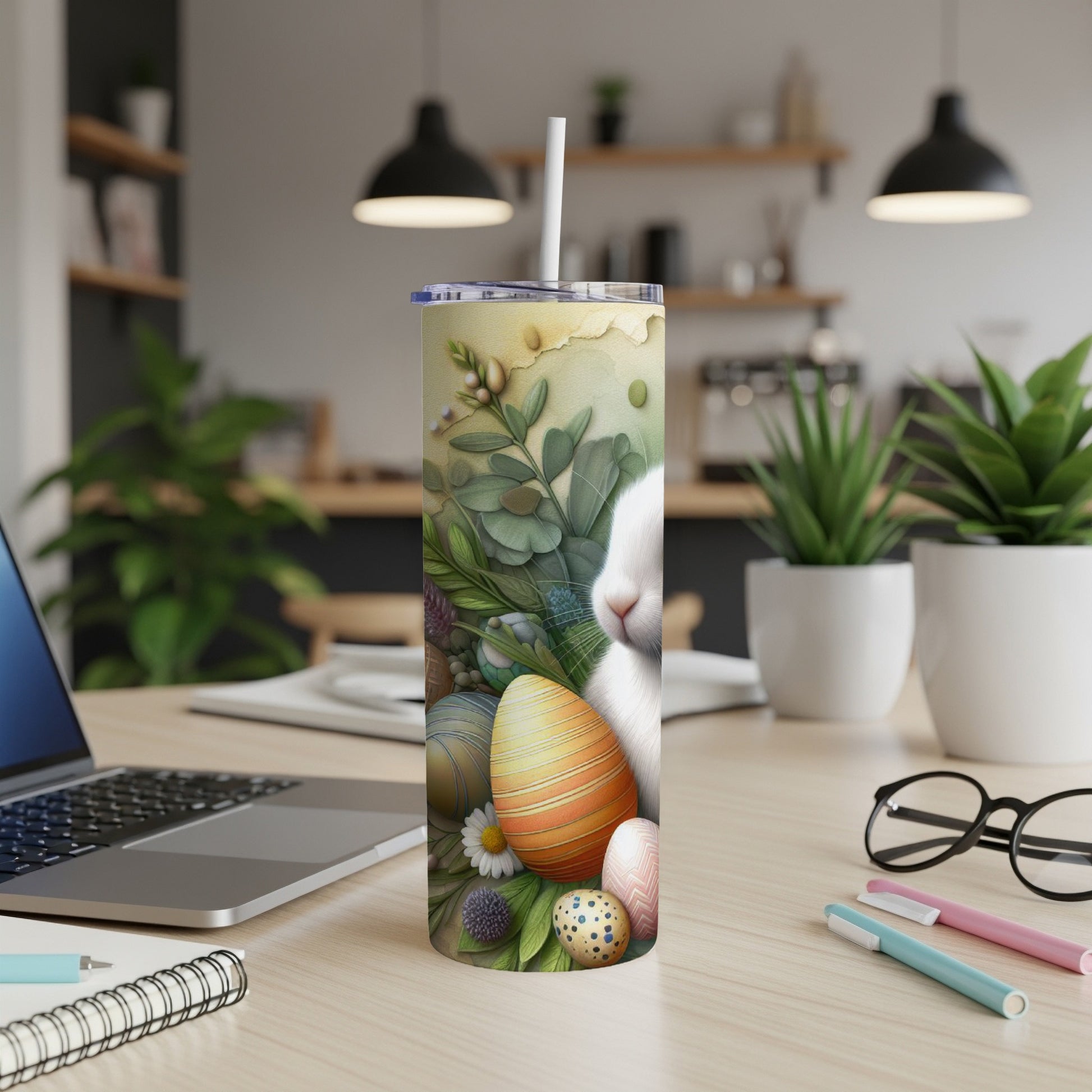 Easter bunny and decorated eggs on a tumbler, with laptop and pens.