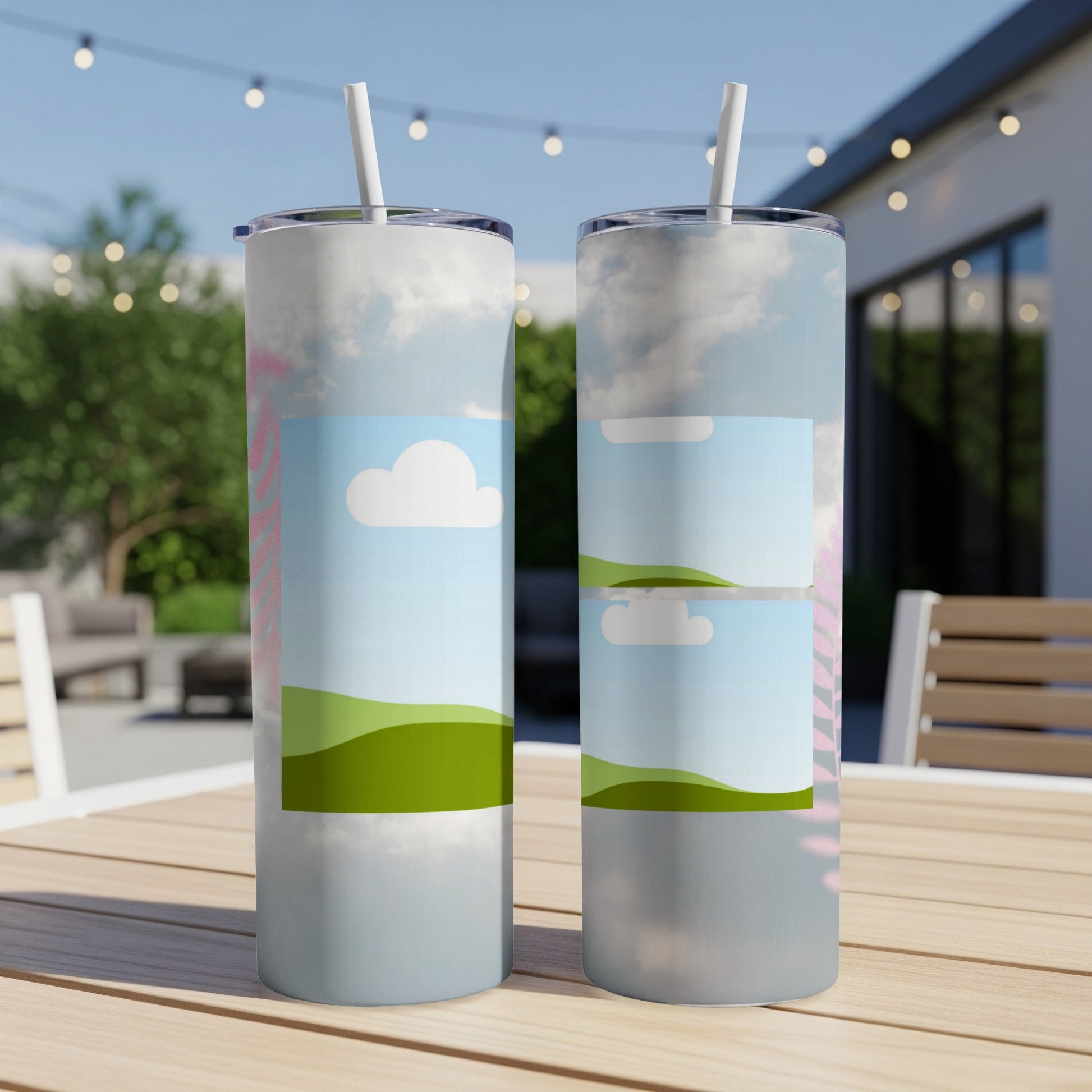 Two tumblers with a sky and green rolling hills design on a wooden table.