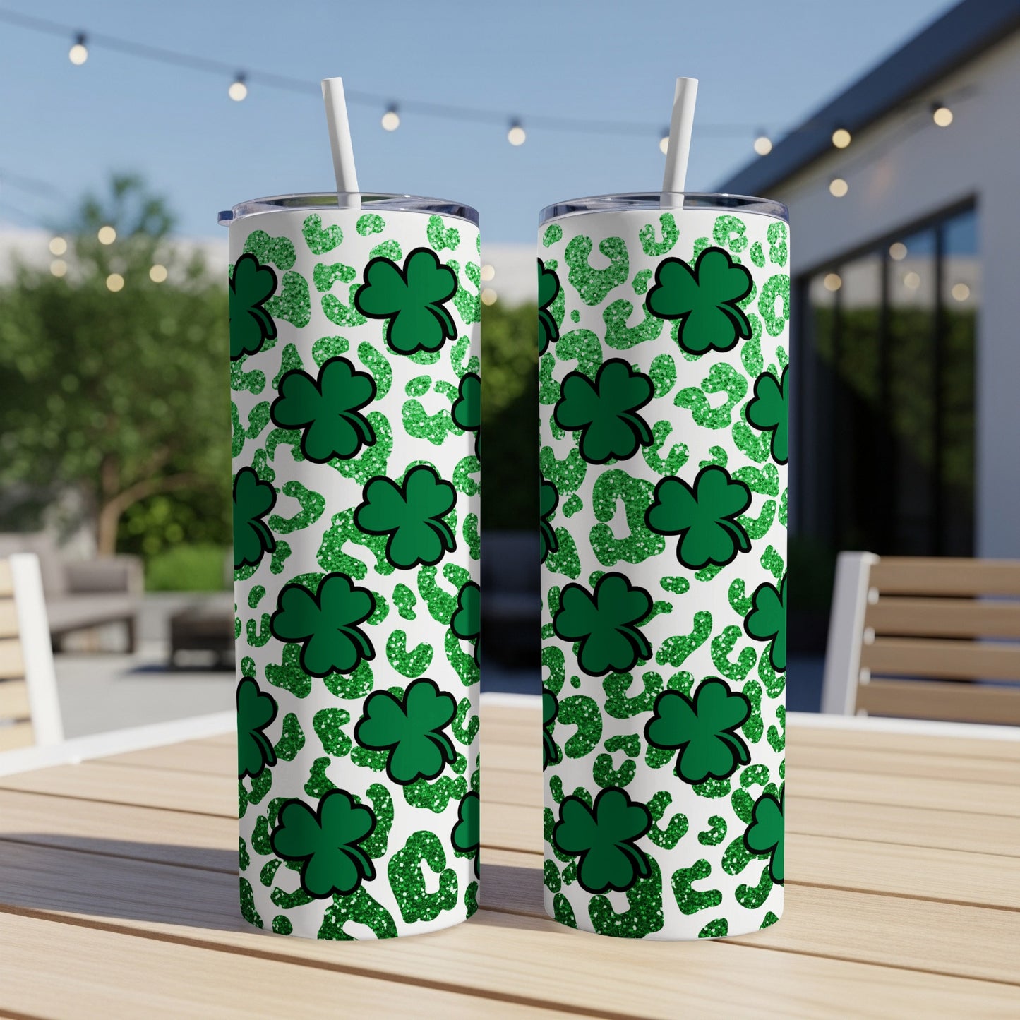 Two glittery green shamrock and leopard print tumblers on a wooden table outdoors.