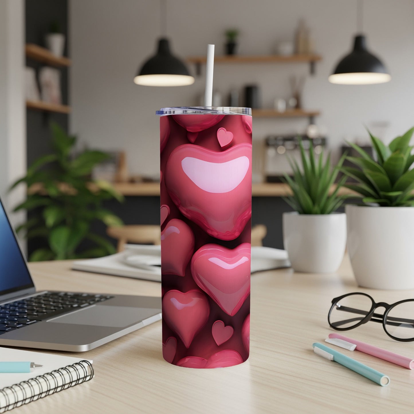 Pink heart pattern tumbler with straw on a wooden desk.