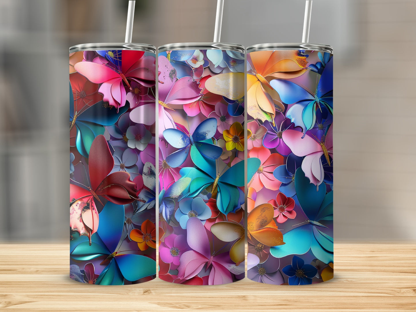 Three colorful butterfly and floral pattern tumblers with straws on a wooden surface.