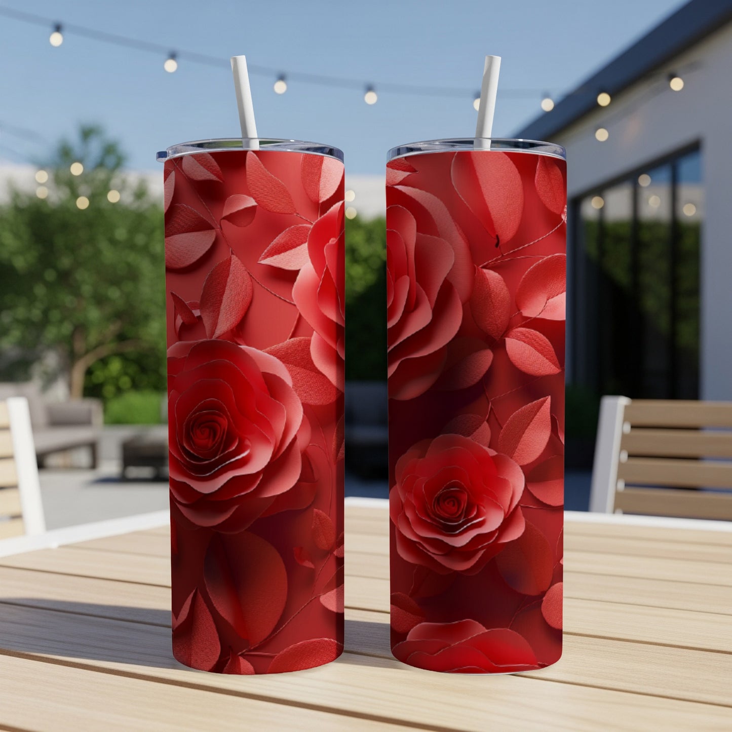 Two red rose patterned tumblers on a wooden table outdoors.