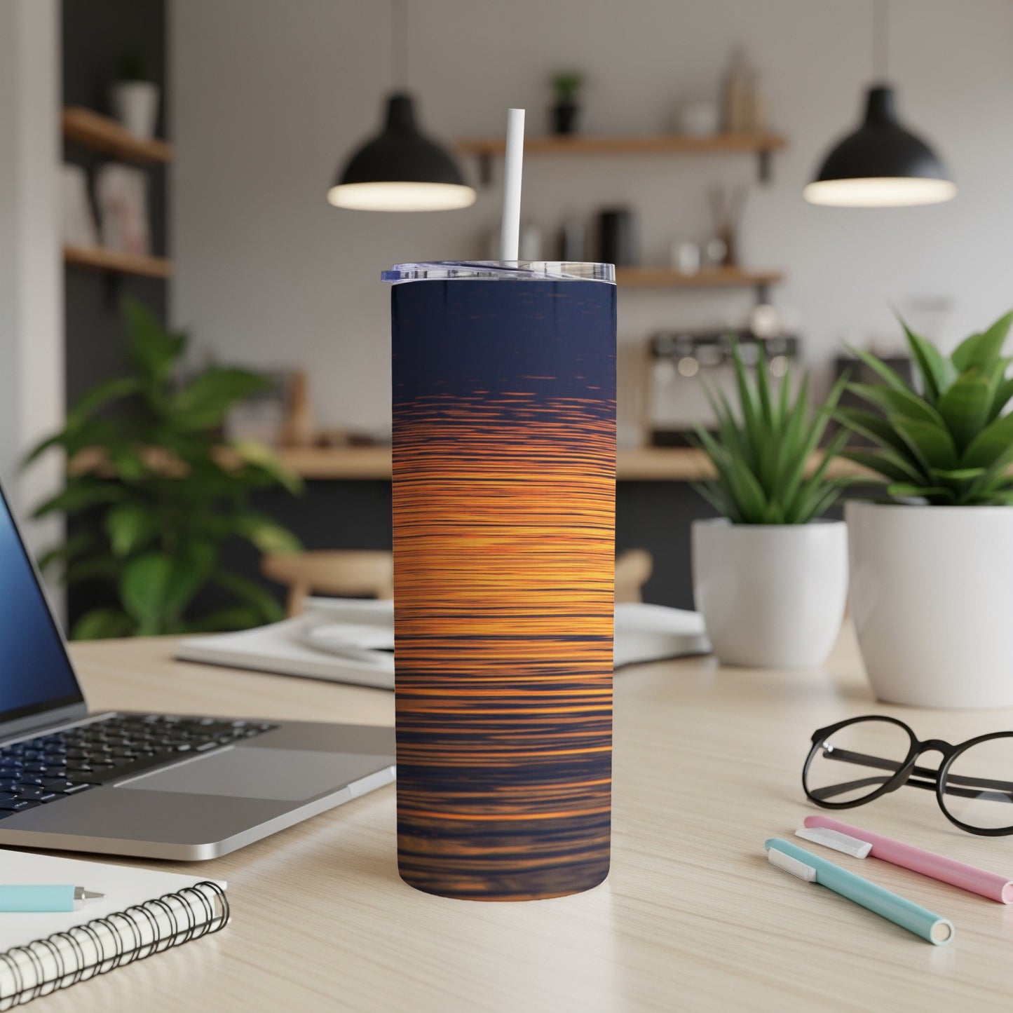 Sunset on water pattern tumbler with straw on desk.