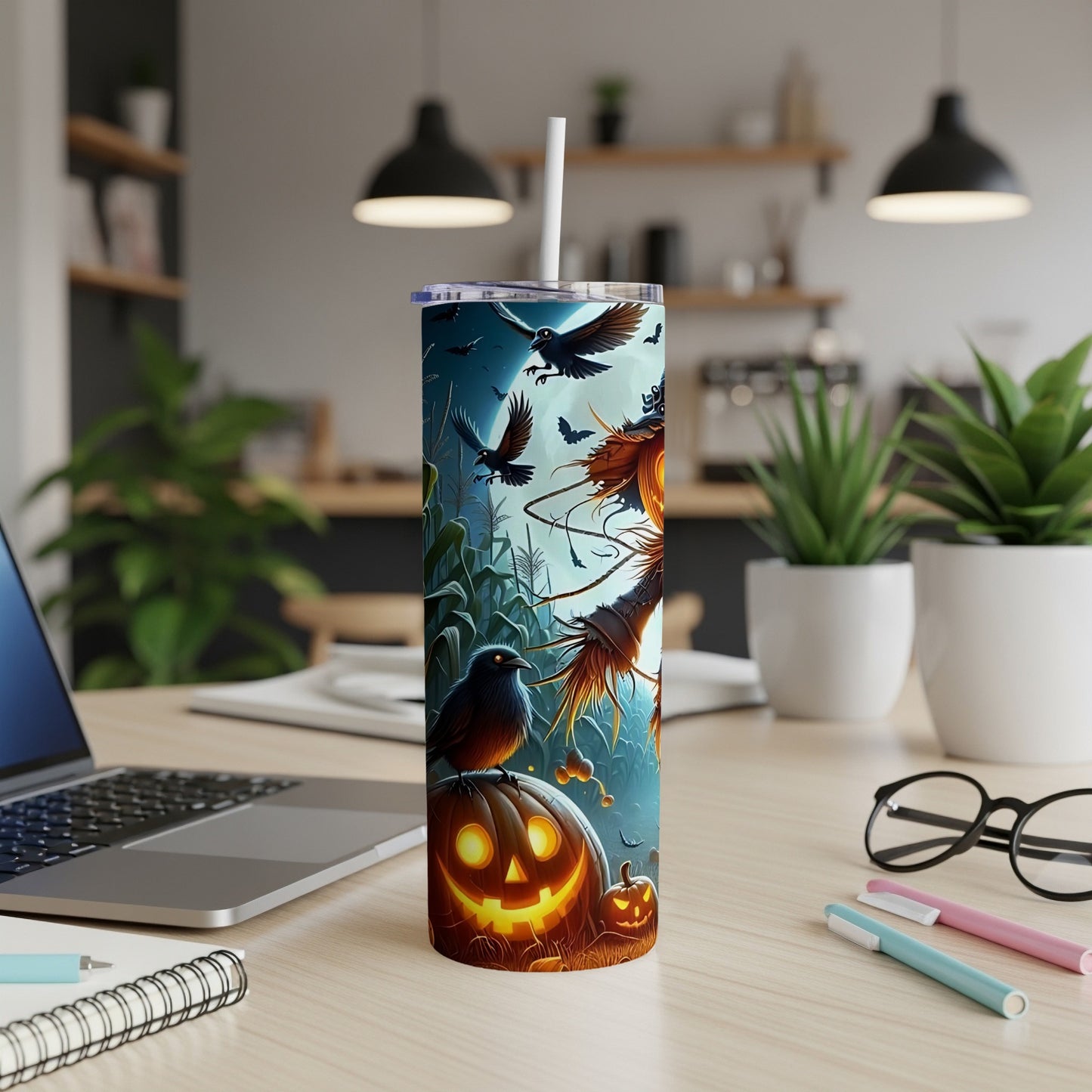Halloween tumbler with scarecrow, crows, bats, and jack-o'-lantern on a desk.