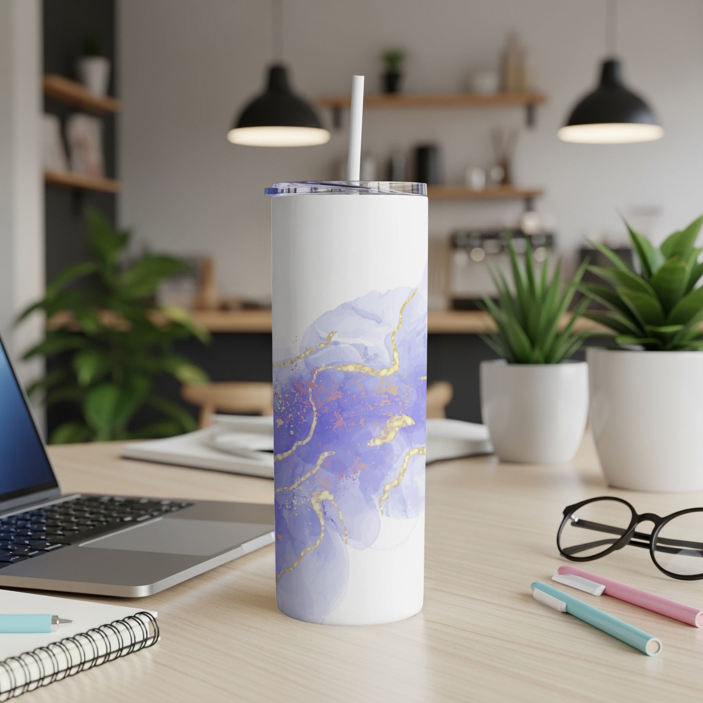 White tumbler with abstract purple and gold marble design and straw.