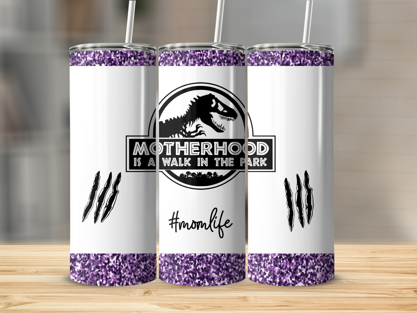 White tumbler with "Motherhood is a walk in the park" and T-Rex logo.