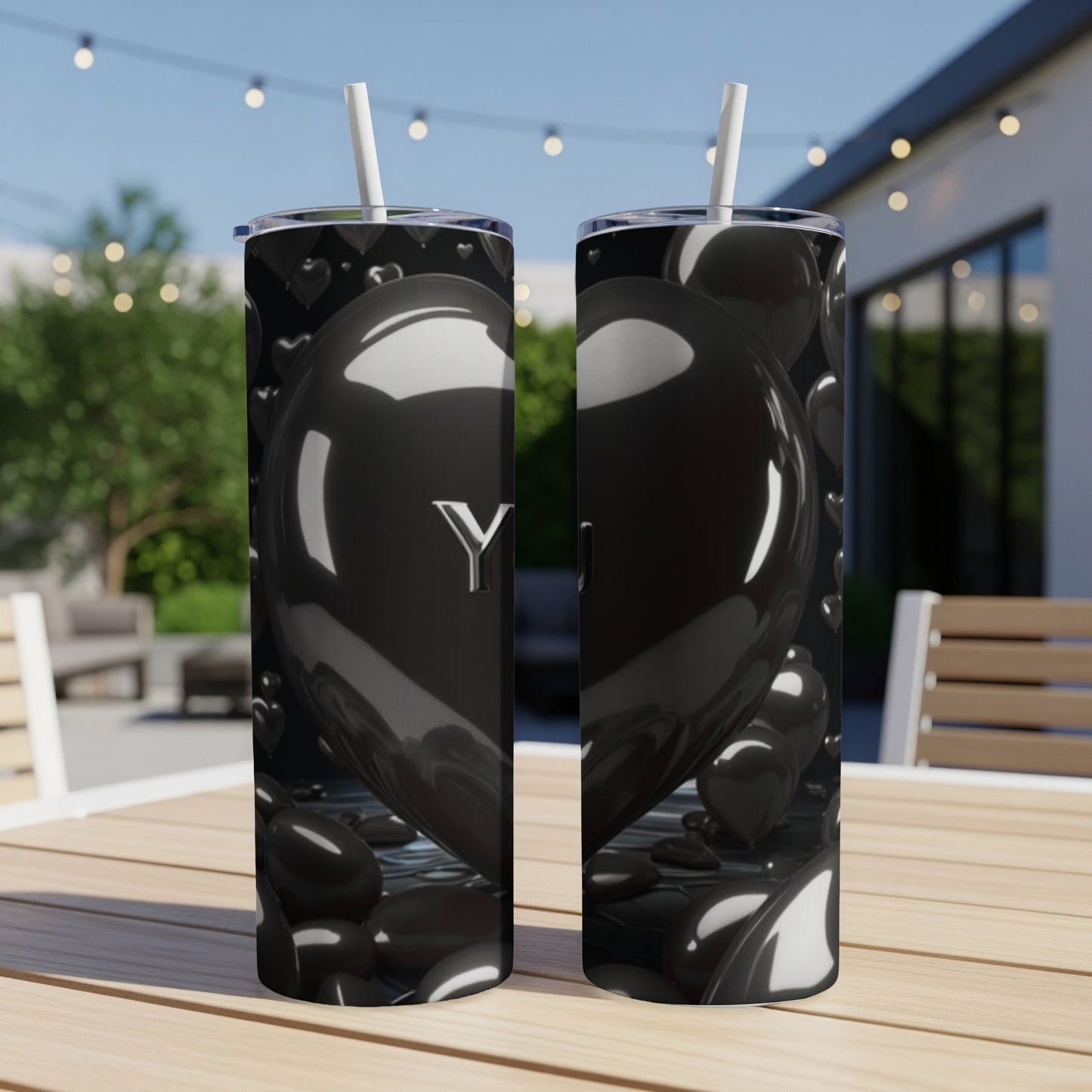 Black heart tumbler with "You" in silver lettering on a table outdoors.