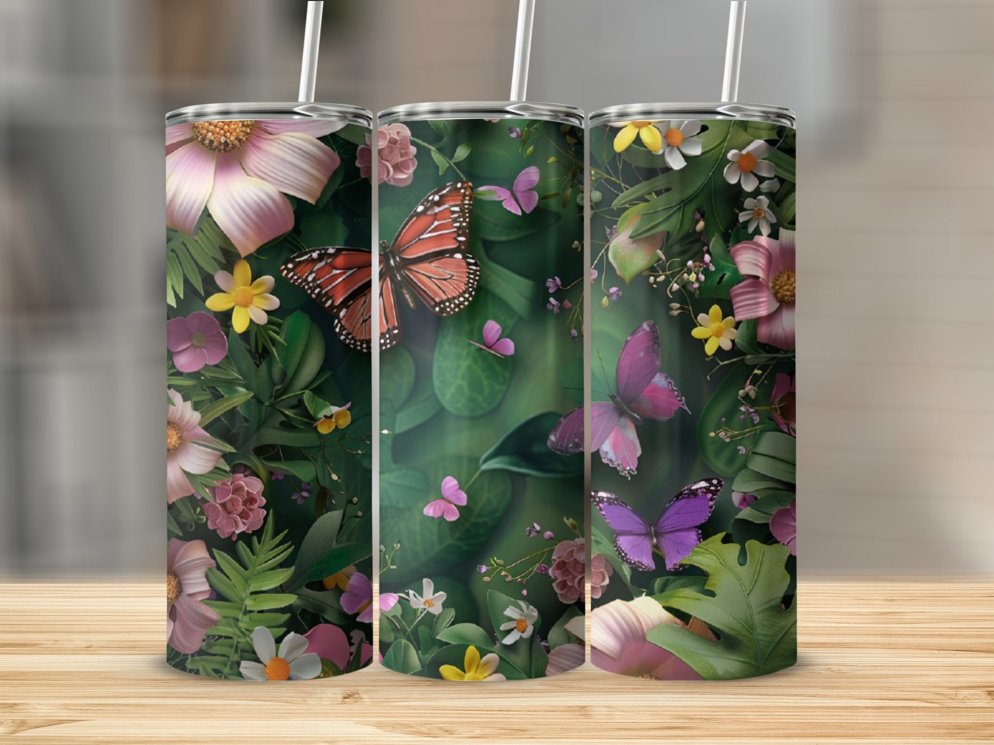 Three tumblers with floral and butterfly designs on a wooden surface.