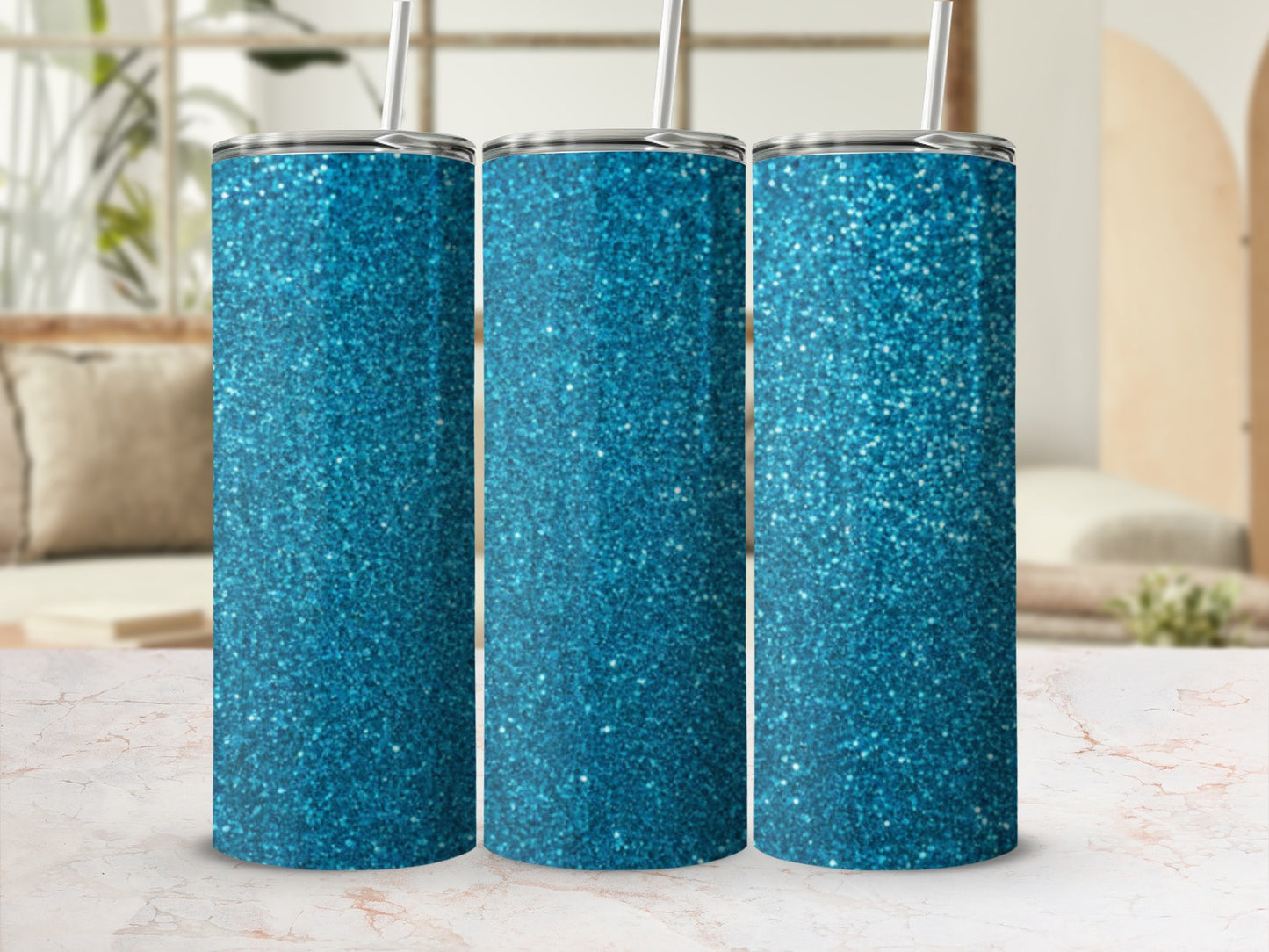 Three blue glitter tumblers with straws on a marble surface.