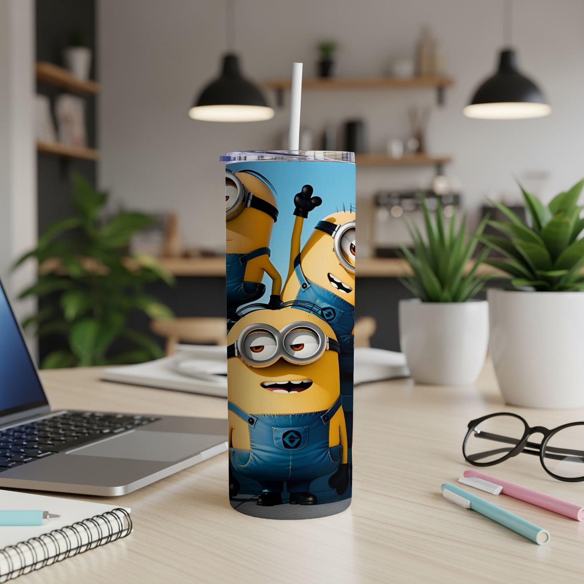 Three Minions in blue overalls stand on a tumbler on a desk.