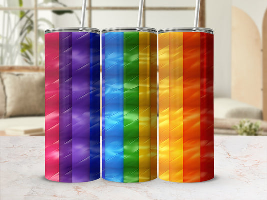 Three rainbow striped tumblers with straws on a marble surface.