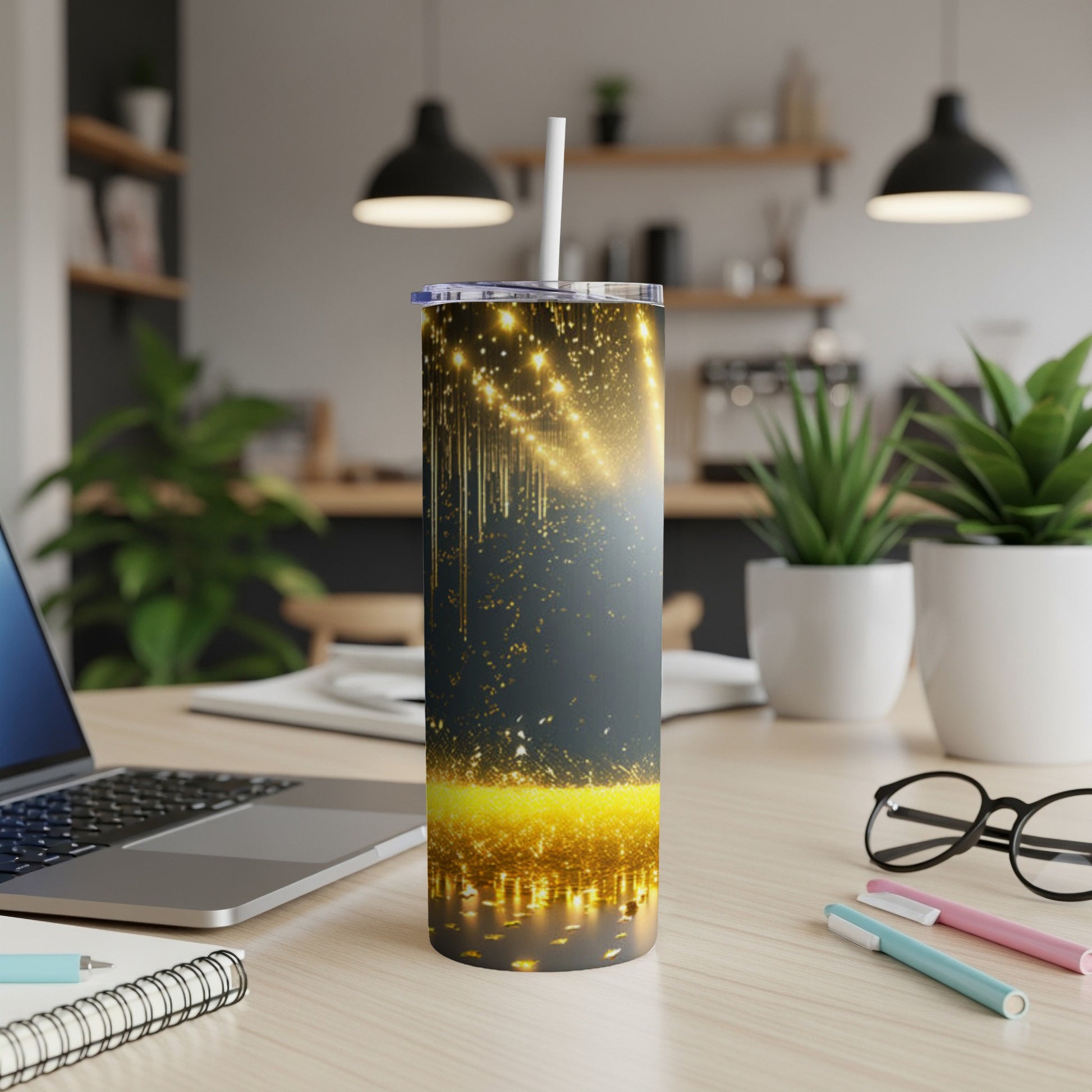 Glittering gold and dark gray tumbler with straw on a desk.