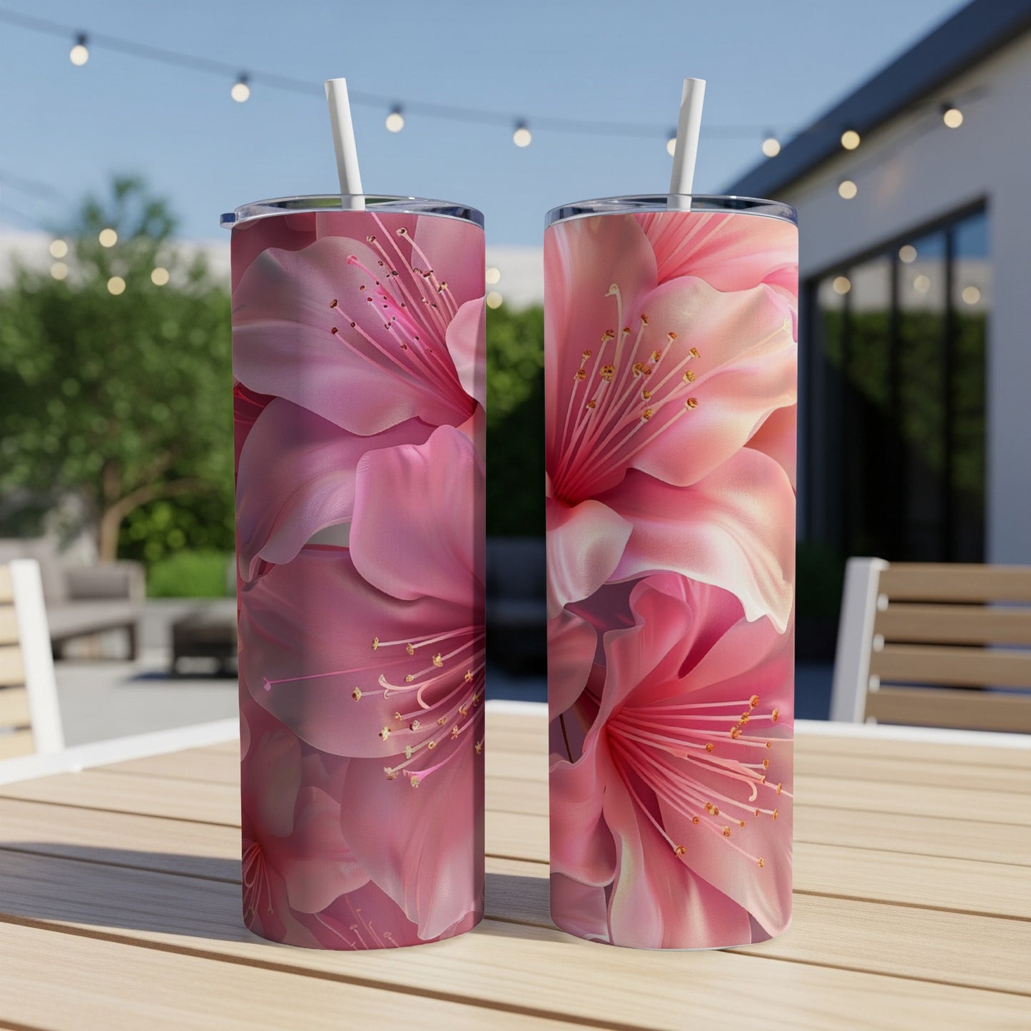 Two pink floral tumblers with straws on a wooden table.