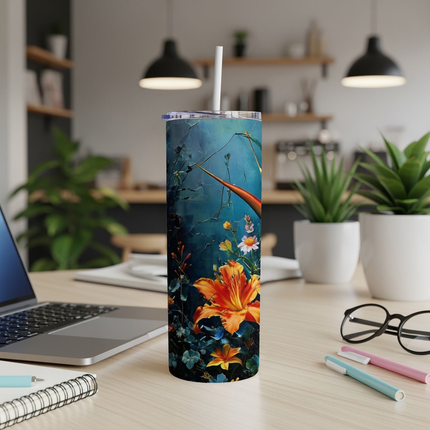 Tall tumbler with orange lilies and blue floral background on a desk.