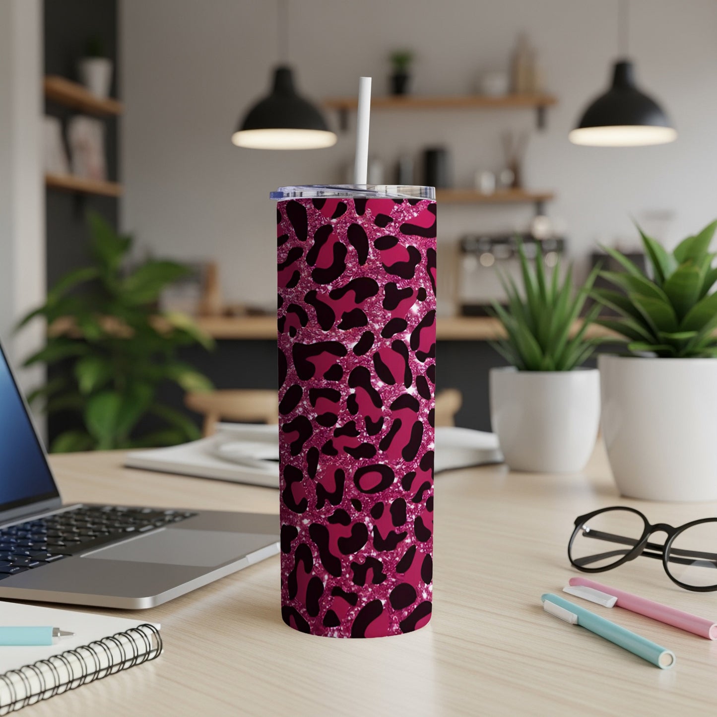 Pink leopard print tumbler with straw on a desk.
