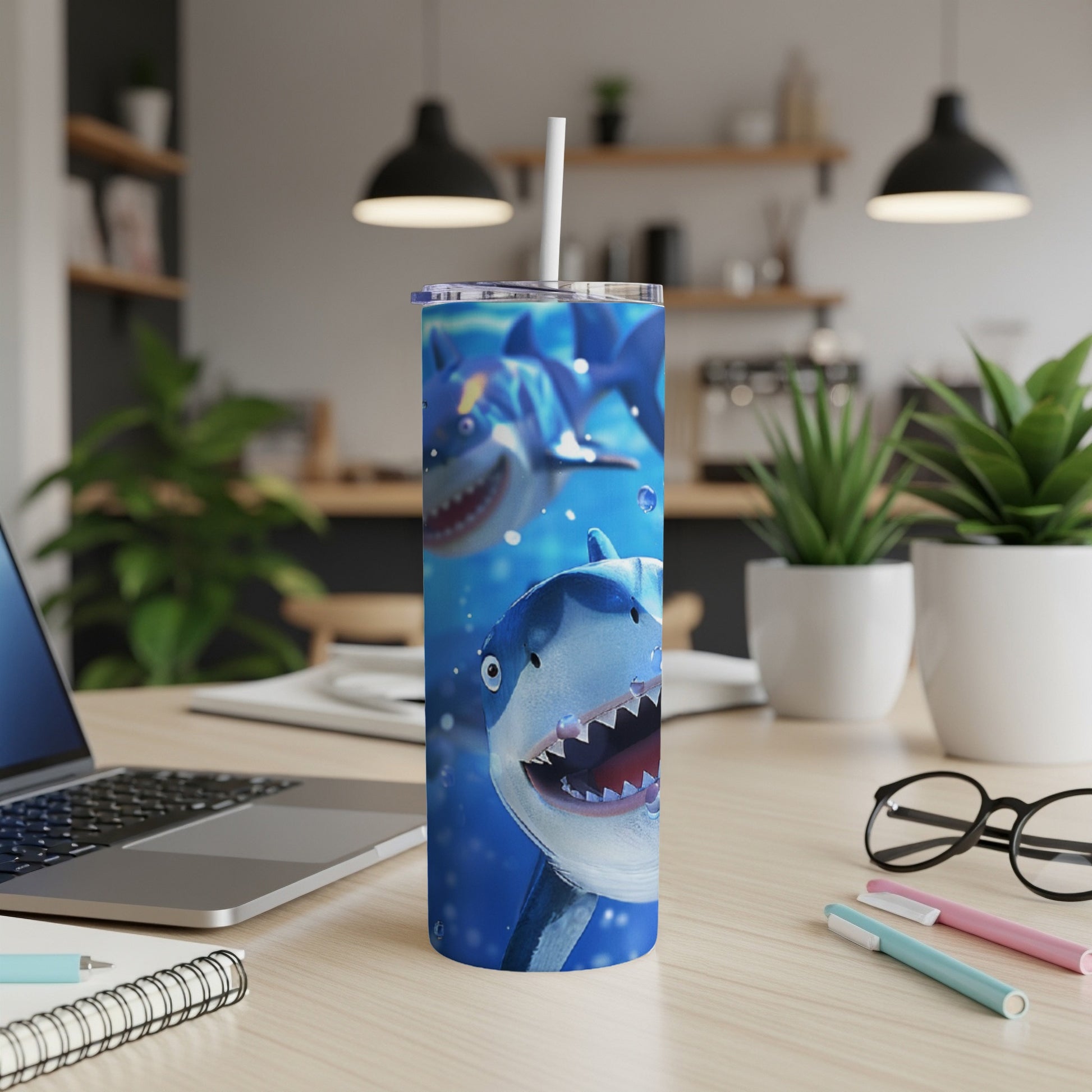 Cartoon sharks on a blue background printed on a tumbler with a white straw.