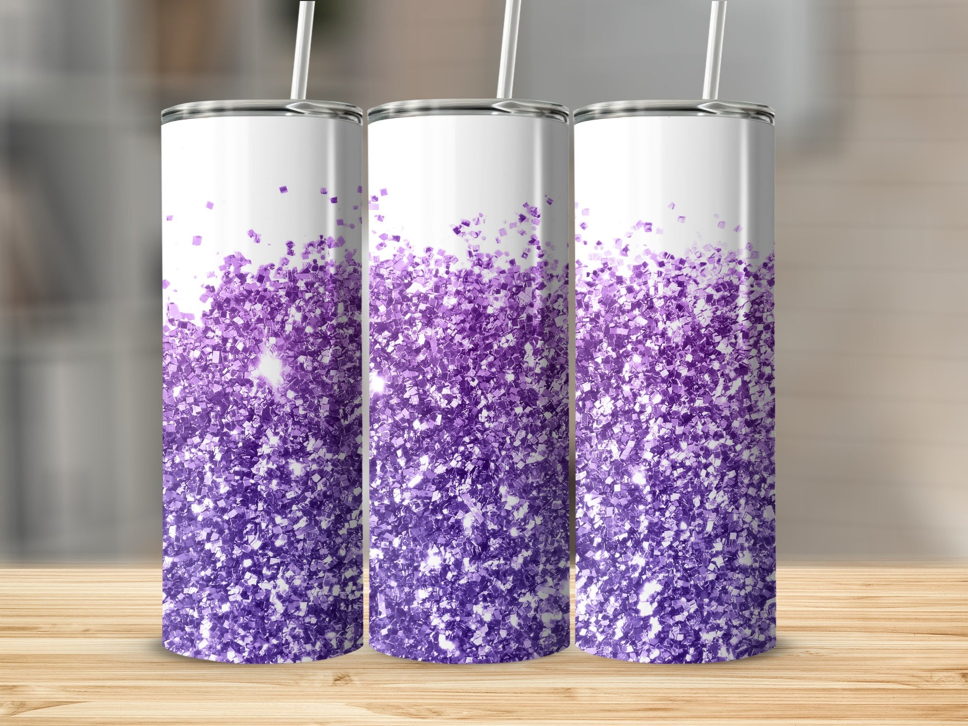 Three tumblers with purple glitter design on a wooden surface.