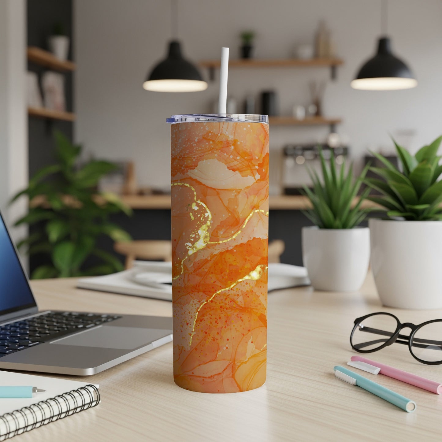 Orange marble patterned tumbler with a white straw on a desk.