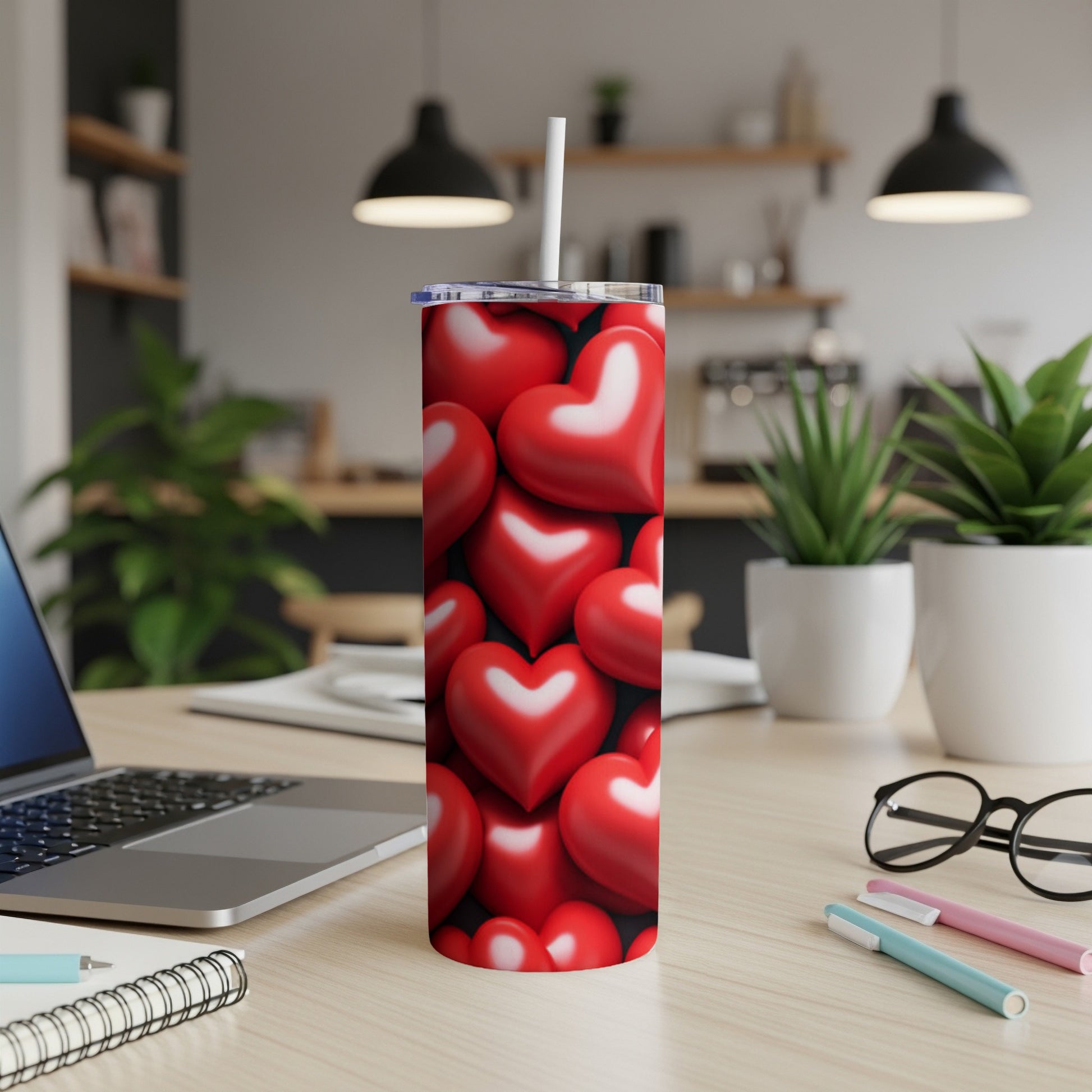Red heart patterned tumbler with white straw on a desk.