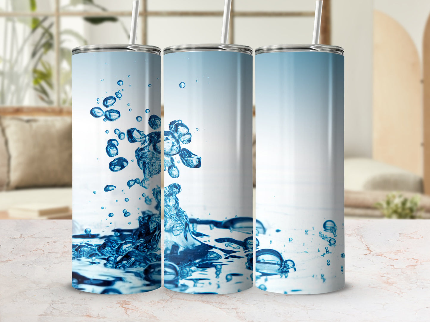 Three tumblers with blue water splash designs on a marble surface.