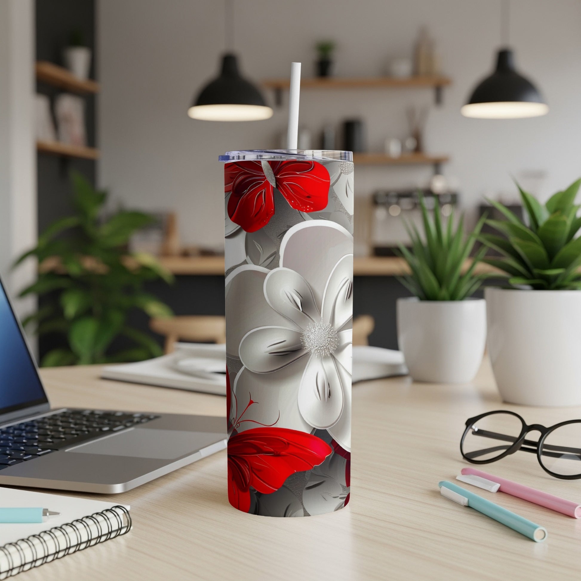 White and red floral and butterfly tumbler with straw on a desk.